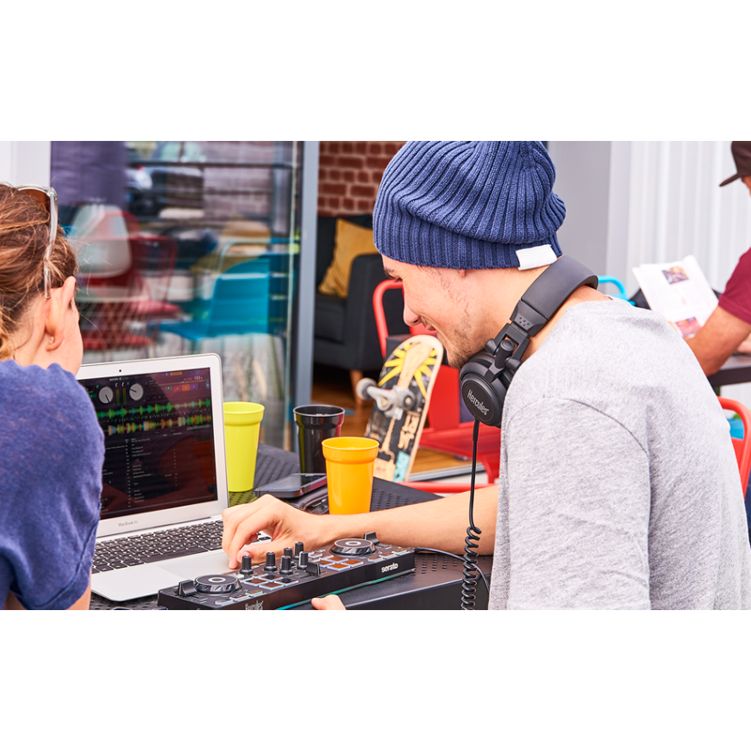 Man die dj-controller gebruikt, met koptelefoon, naast een laptop.