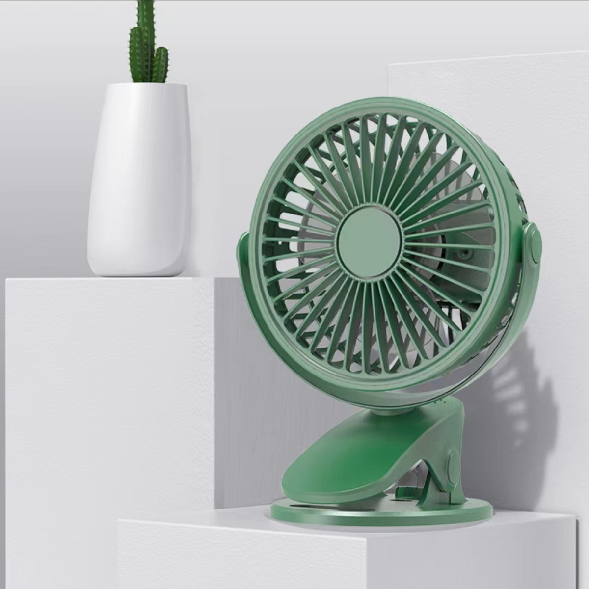 Grüner Mini-Ventilator mit einem weißen Blumentopf im Hintergrund.