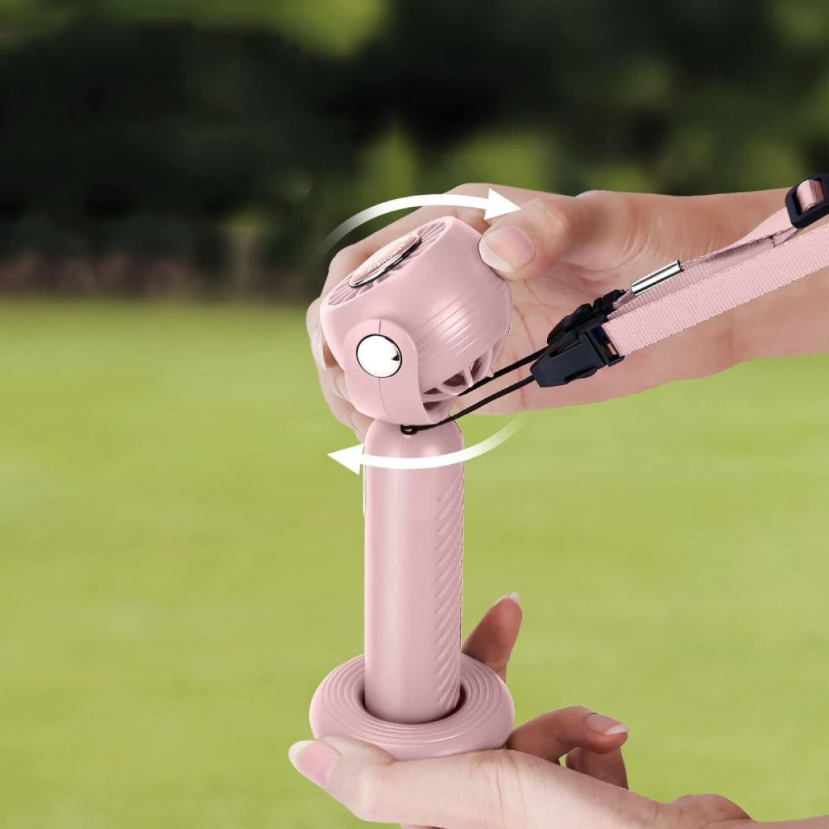 Ein rosa Handventilator, der von einer Person gedreht wird. Der Hintergrund ist grün.