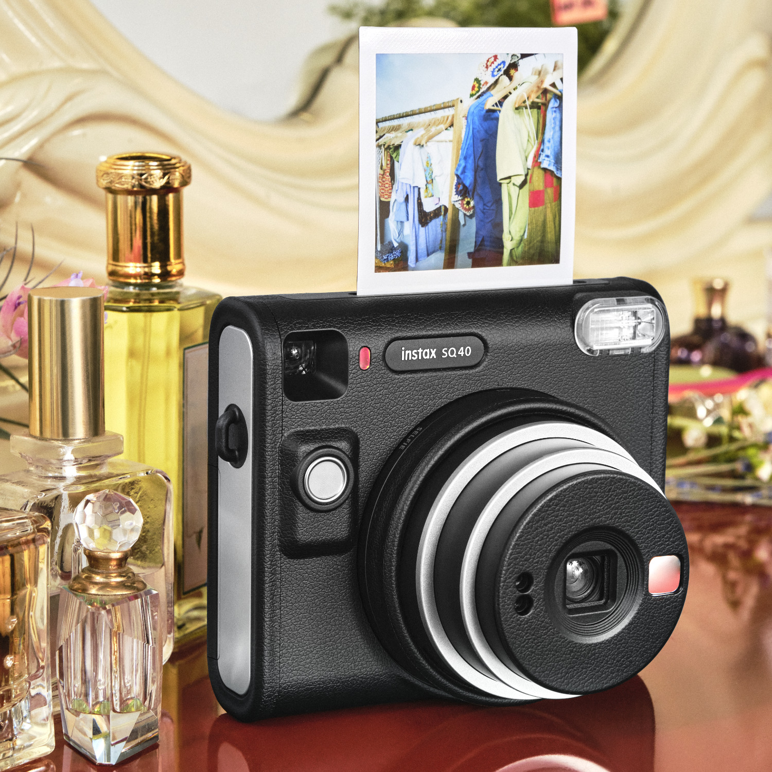 Schwarze Instax-Kamera mit Foto, Parfümflaschen auf dem Tisch und Hintergrund.