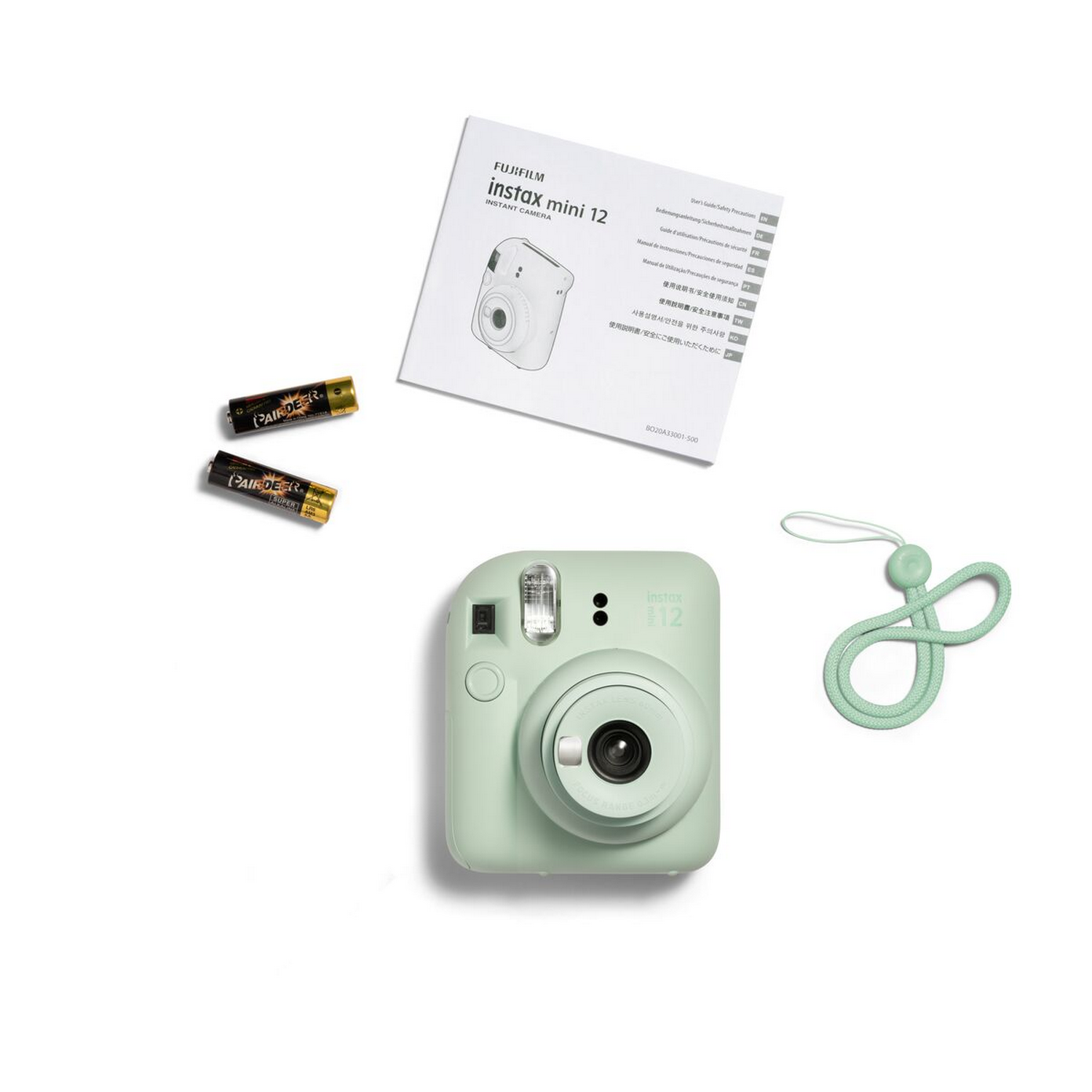Nane yeşili bir Instax Mini 12 fotoğraf makinesi, piller, bir kayış ve beyaz bir yüzeyde bir kılavuz.