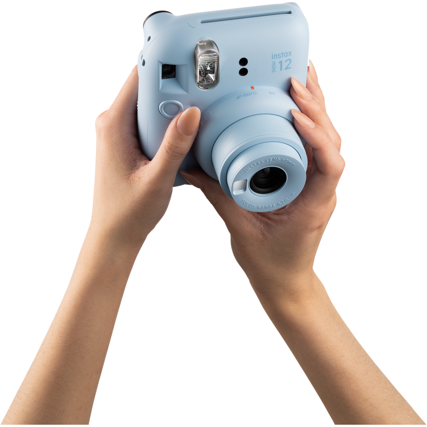 Eller, açık mavi bir Instax kamera tutuyor, lens görünür durumda.