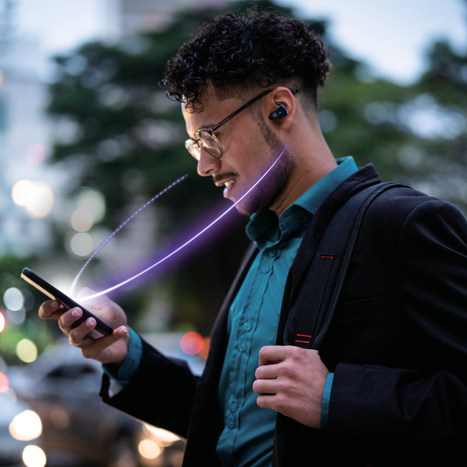 Un hombre con gafas mira su teléfono, con auriculares inalámbricos.