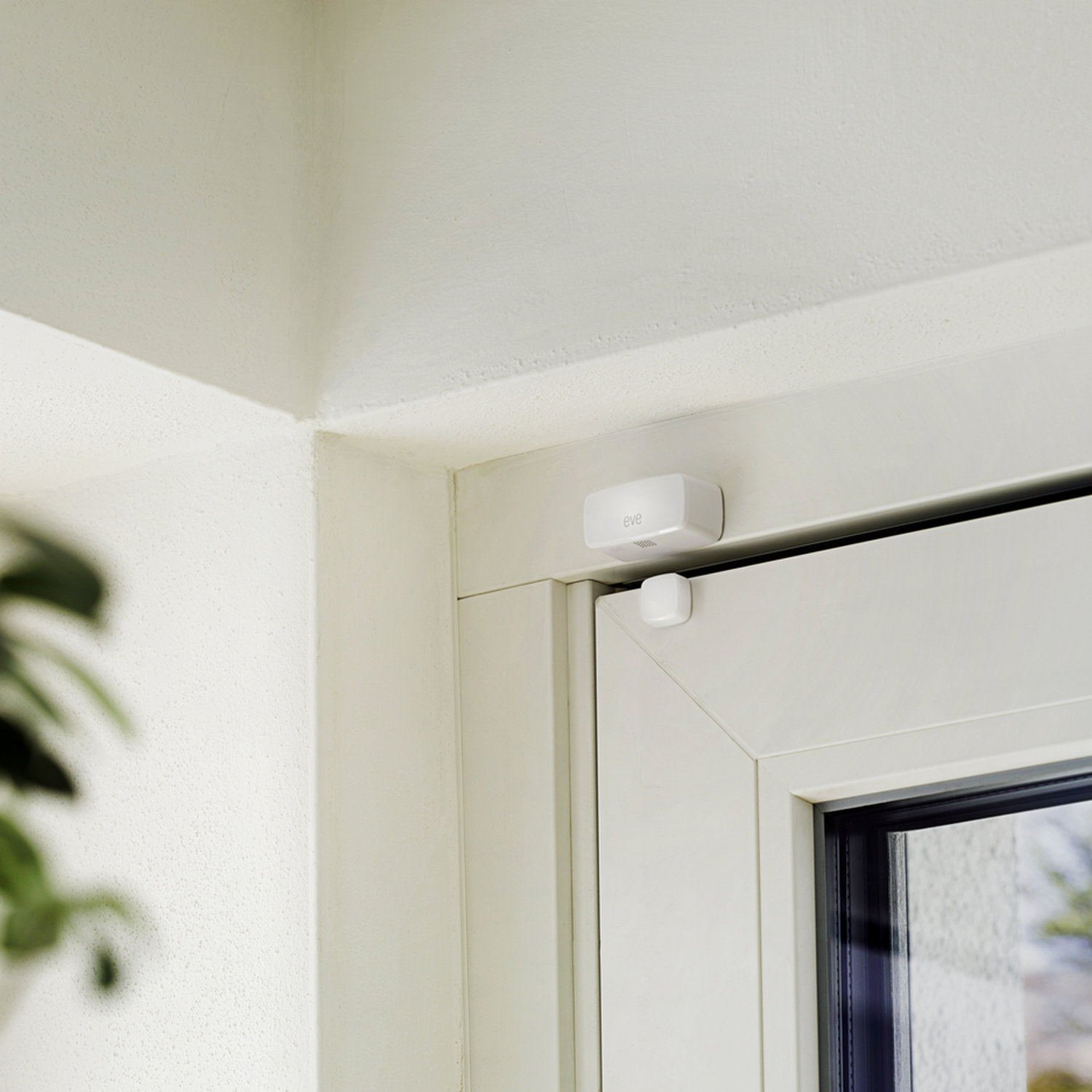 Biała rama okienna z małym, białym czujnikiem zainstalowanym na ramie.