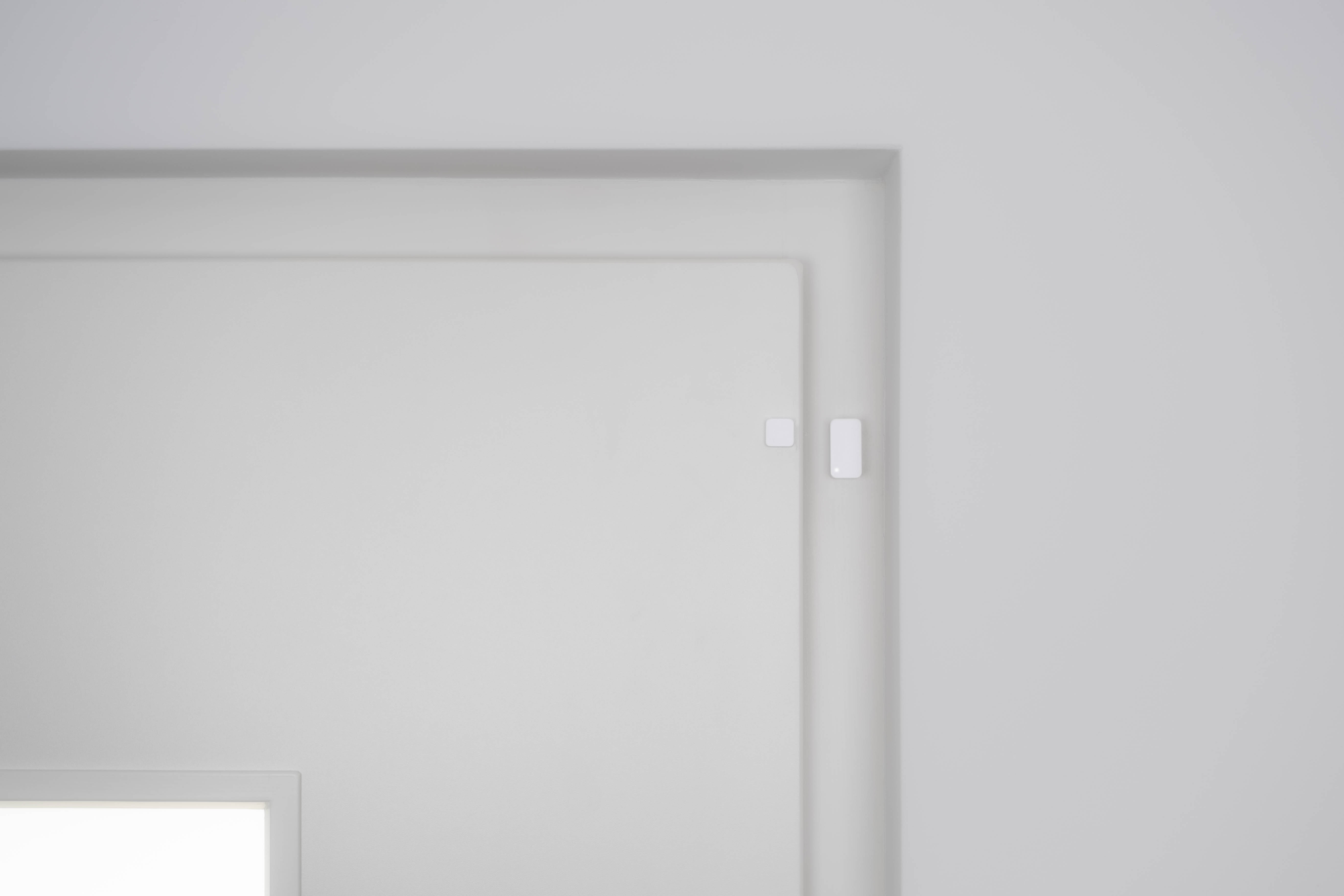 White door frame with a door slightly ajar. White walls and a white door.