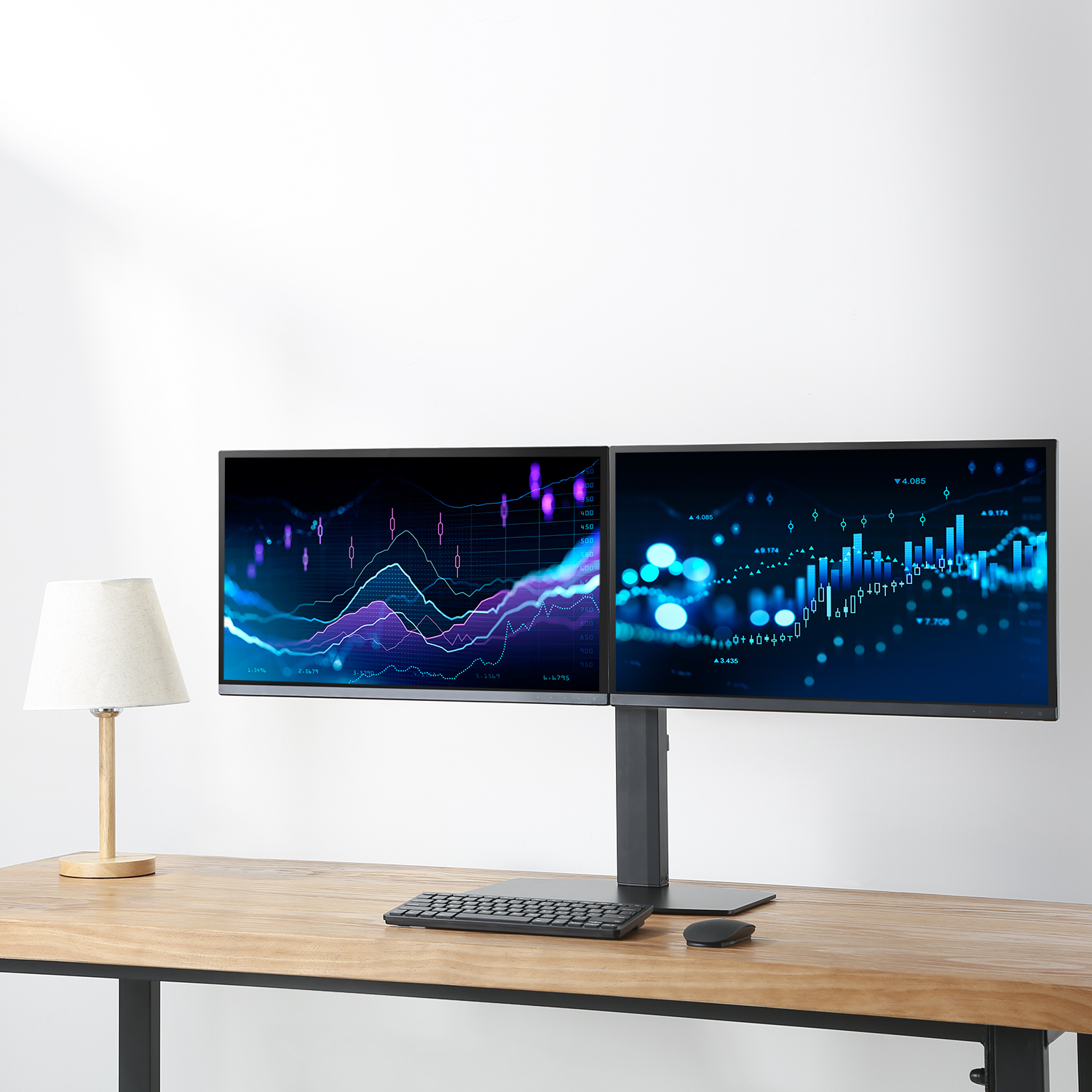 Dwa monitory komputerowe wyświetlające dane finansowe na drewnianym biurku z lampą i klawiaturą.