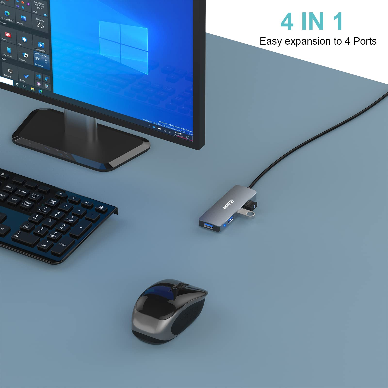 Ein Computer-Setup mit Monitor, Tastatur, Maus und einem grauen USB-Hub, alles auf blauer Oberfläche.