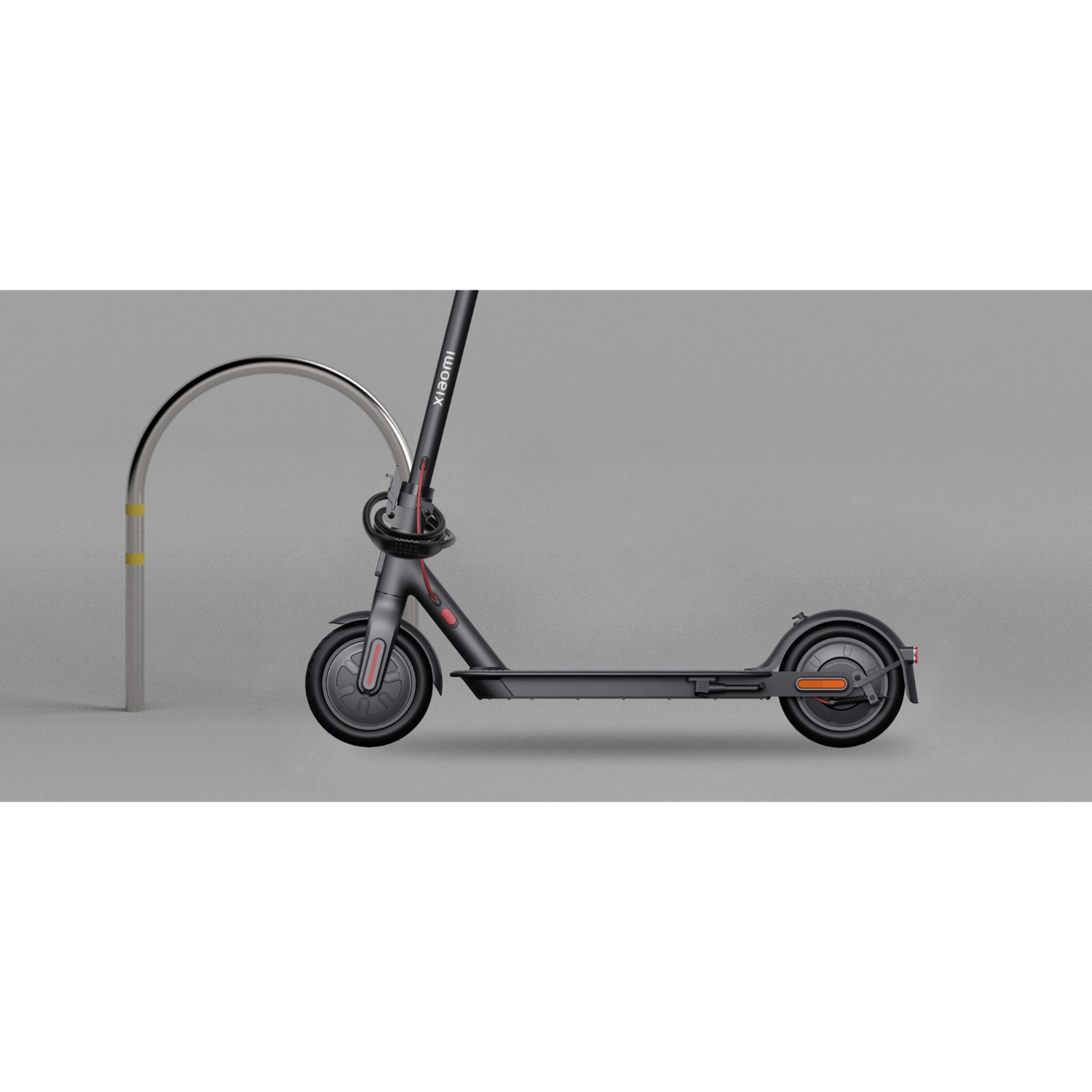 Patinete eléctrico Xiaomi negro y gris estacionado cerca de un estante curvo plateado. Fondo gris.