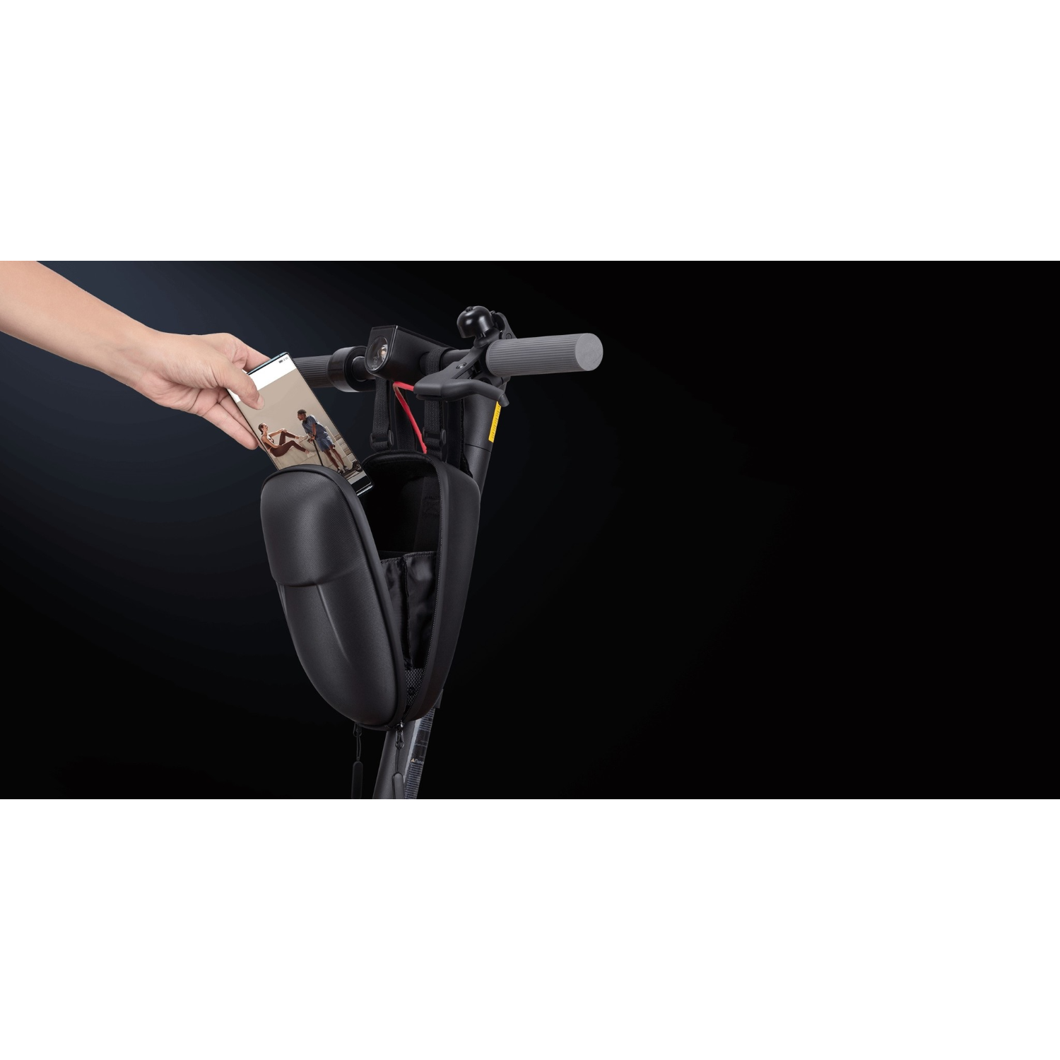 Hand hält ein Telefon und steckt es in eine schwarze Scootertasche am Lenker.