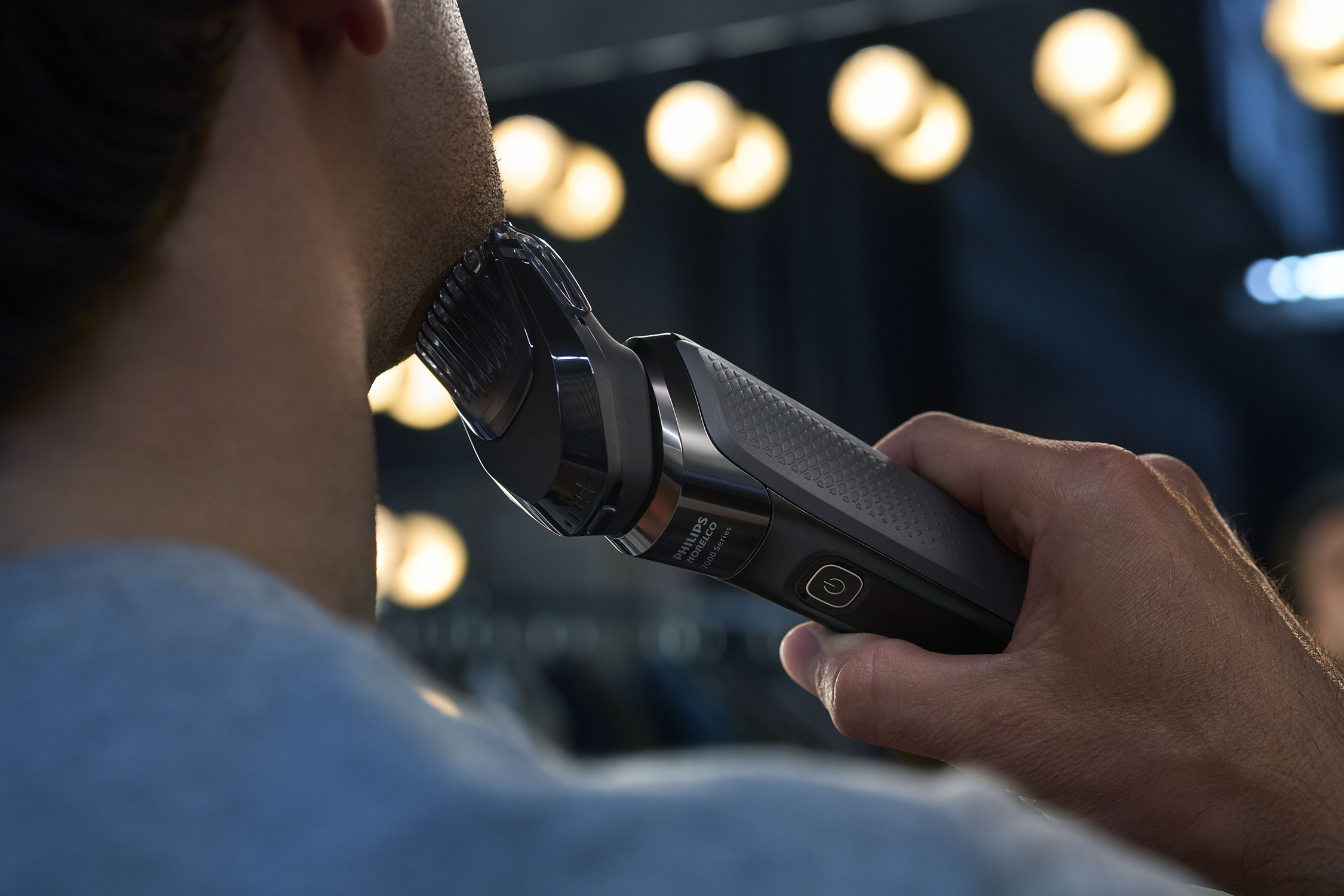 Un homme se rasant la barbe avec un rasoir Philips noir et gris. Gros plan.