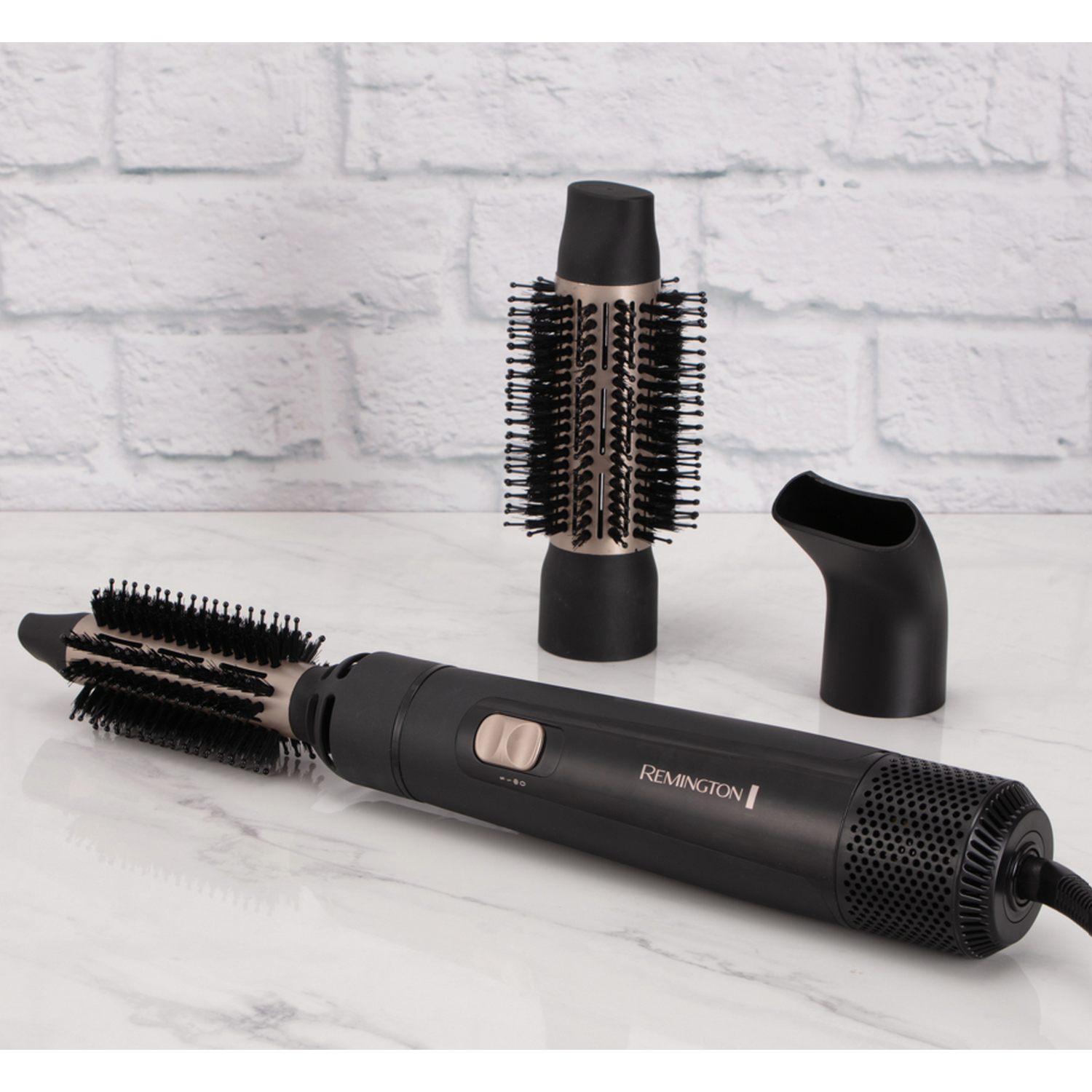 Secador de pelo negro con accesorios sobre una superficie de mármol blanco. Fondo de ladrillos blancos. Tres piezas.