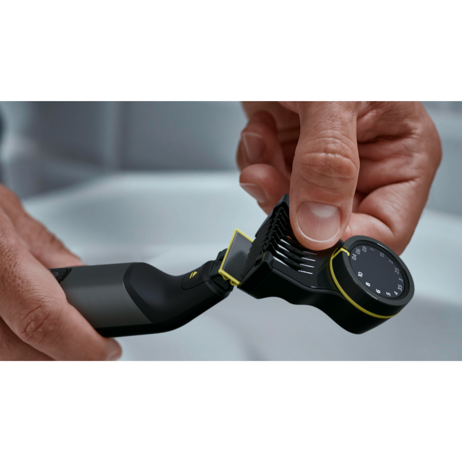 A man holds a beard trimmer. Black and gray with yellow accents. Adjustable length dial visible.