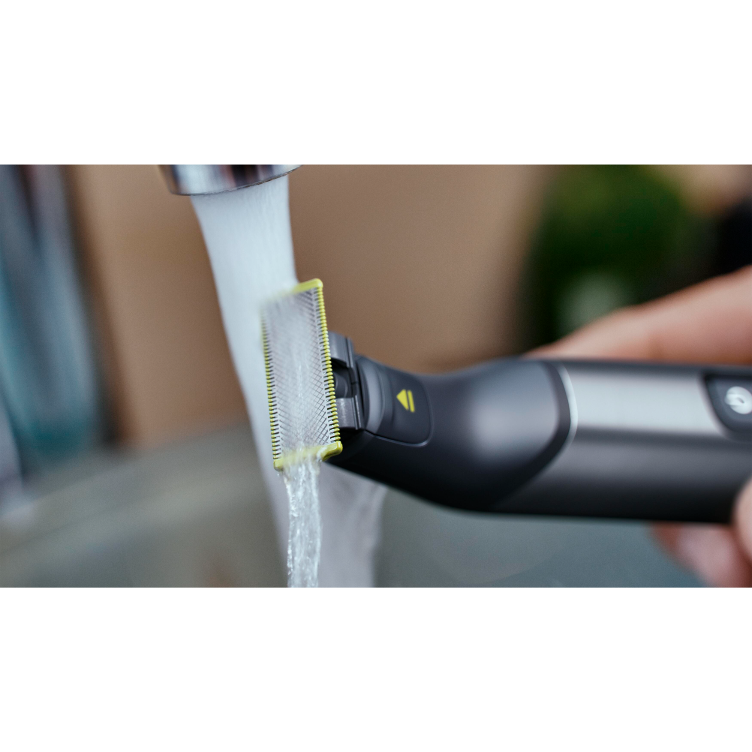 Close up of a black trimmer being rinsed under running water.