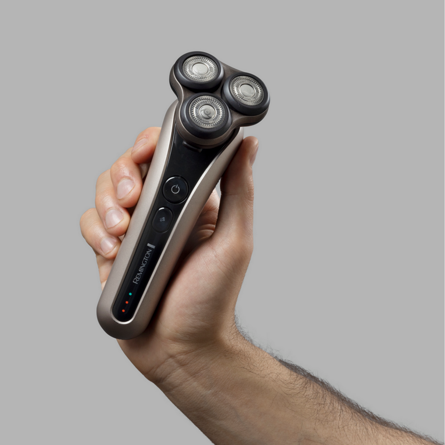 Una mano che tiene un rasoio elettrico Remington. Il rasoio è grigio e nero.