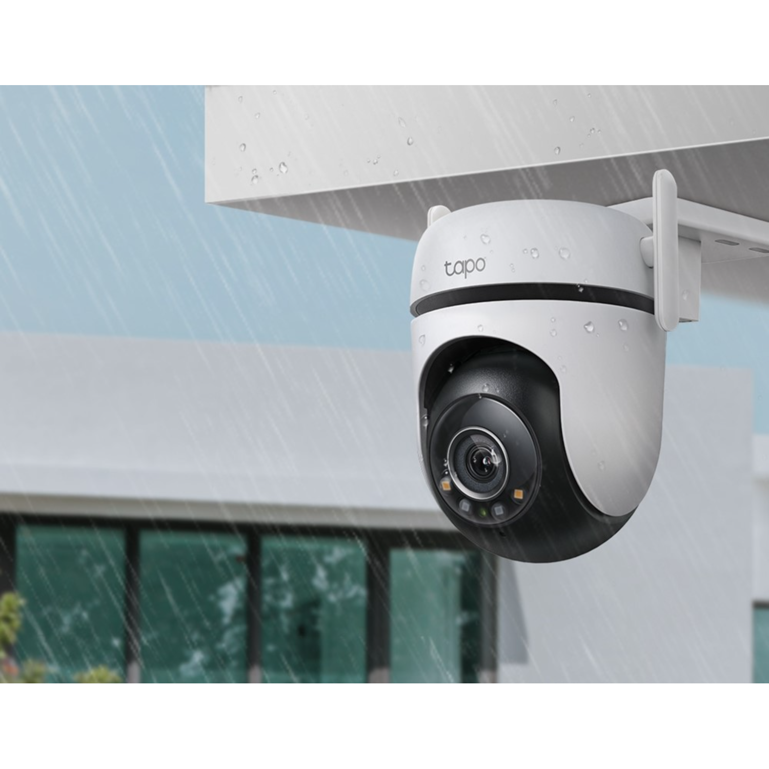 Biała i czarna kamera bezpieczeństwa w deszczu. Budynek w tle.