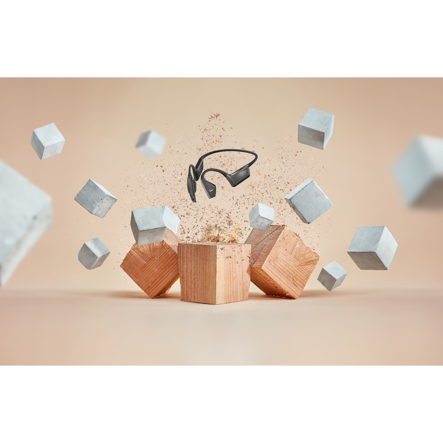 Cuffie nere tra cubi di legno e blocchi di cemento, su sfondo beige.