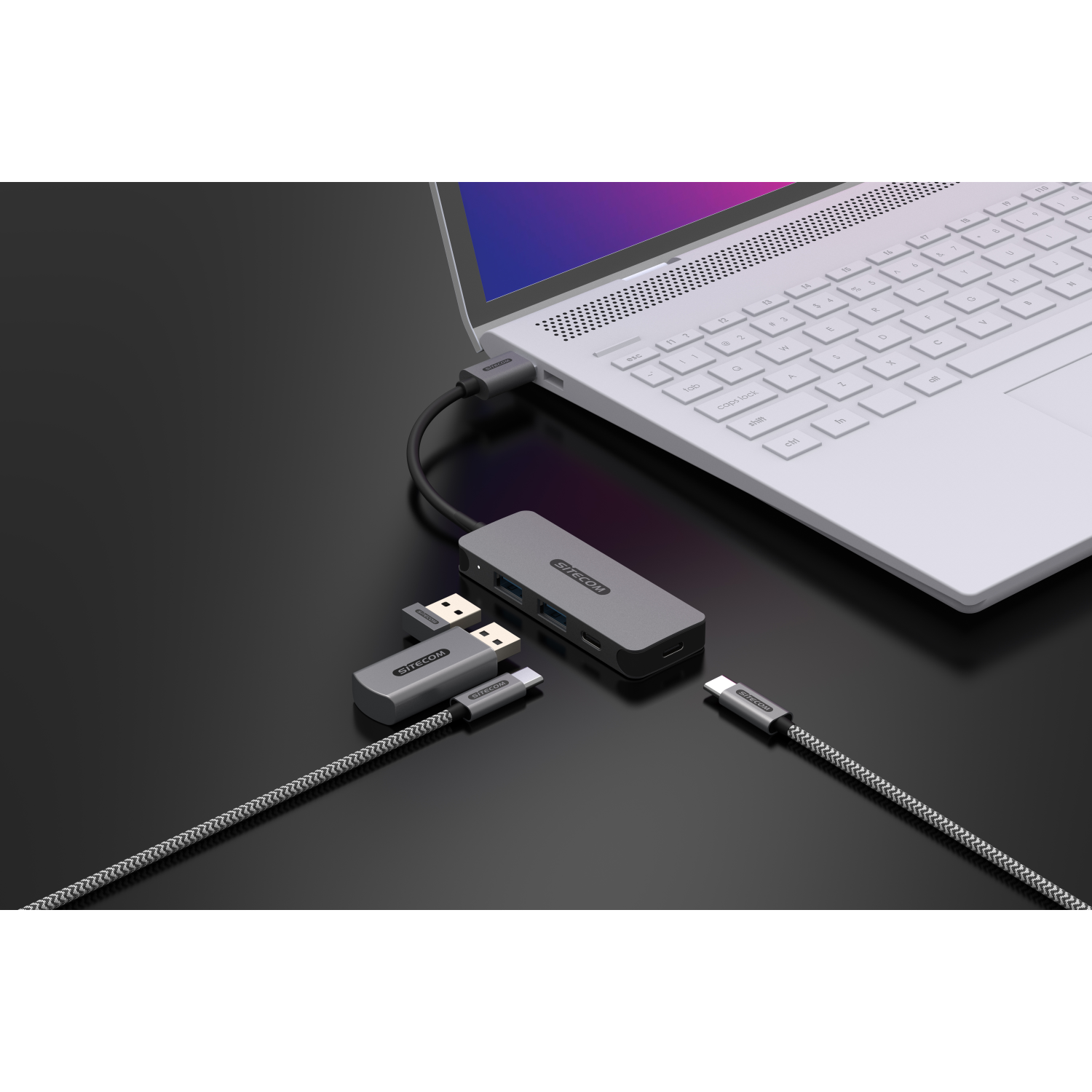 Laptop with connected devices, including USB hubs and cables.