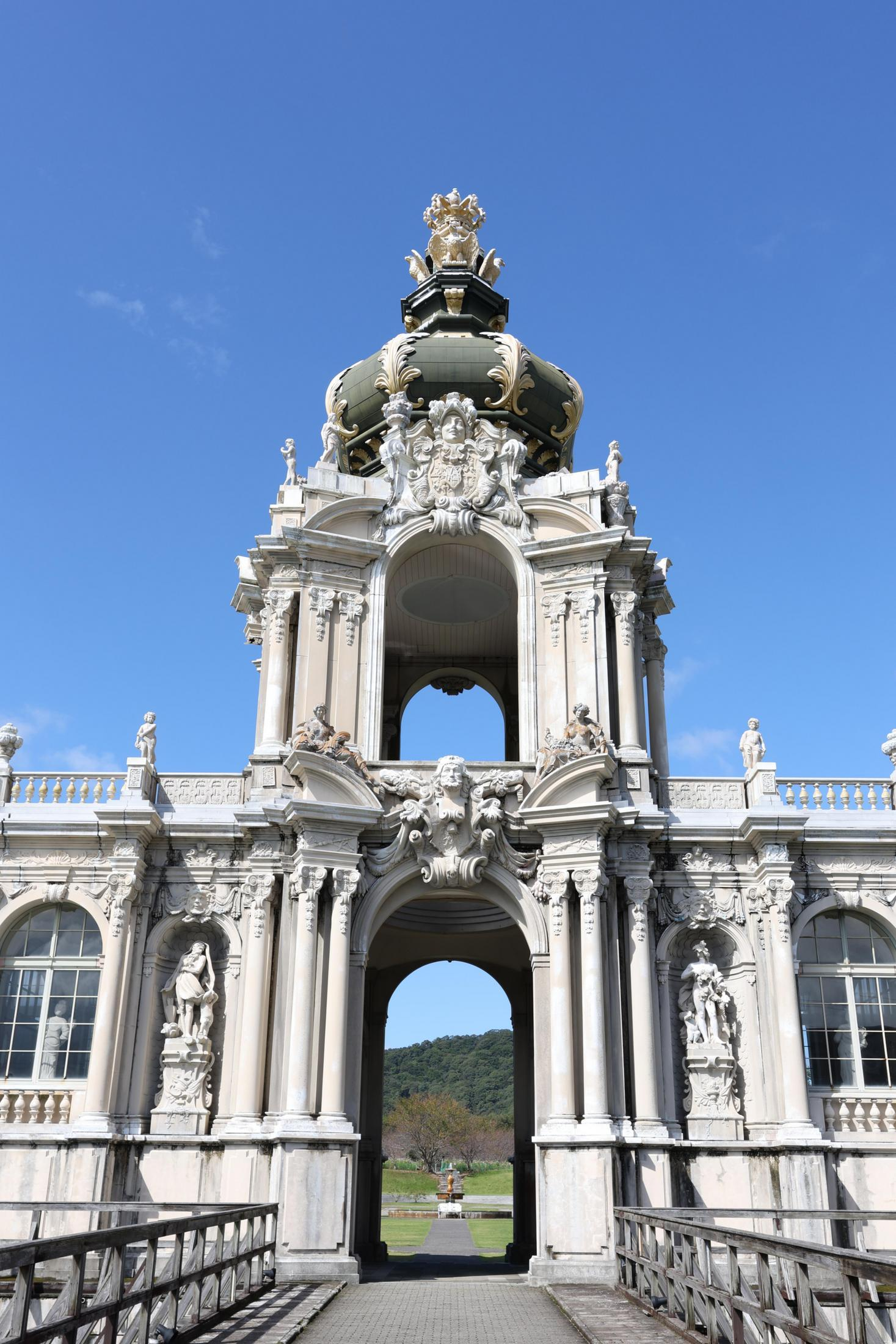 Süslemeli detayları, kemerli girişi ve mavi gökyüzü arka planı olan görkemli beyaz bir bina.