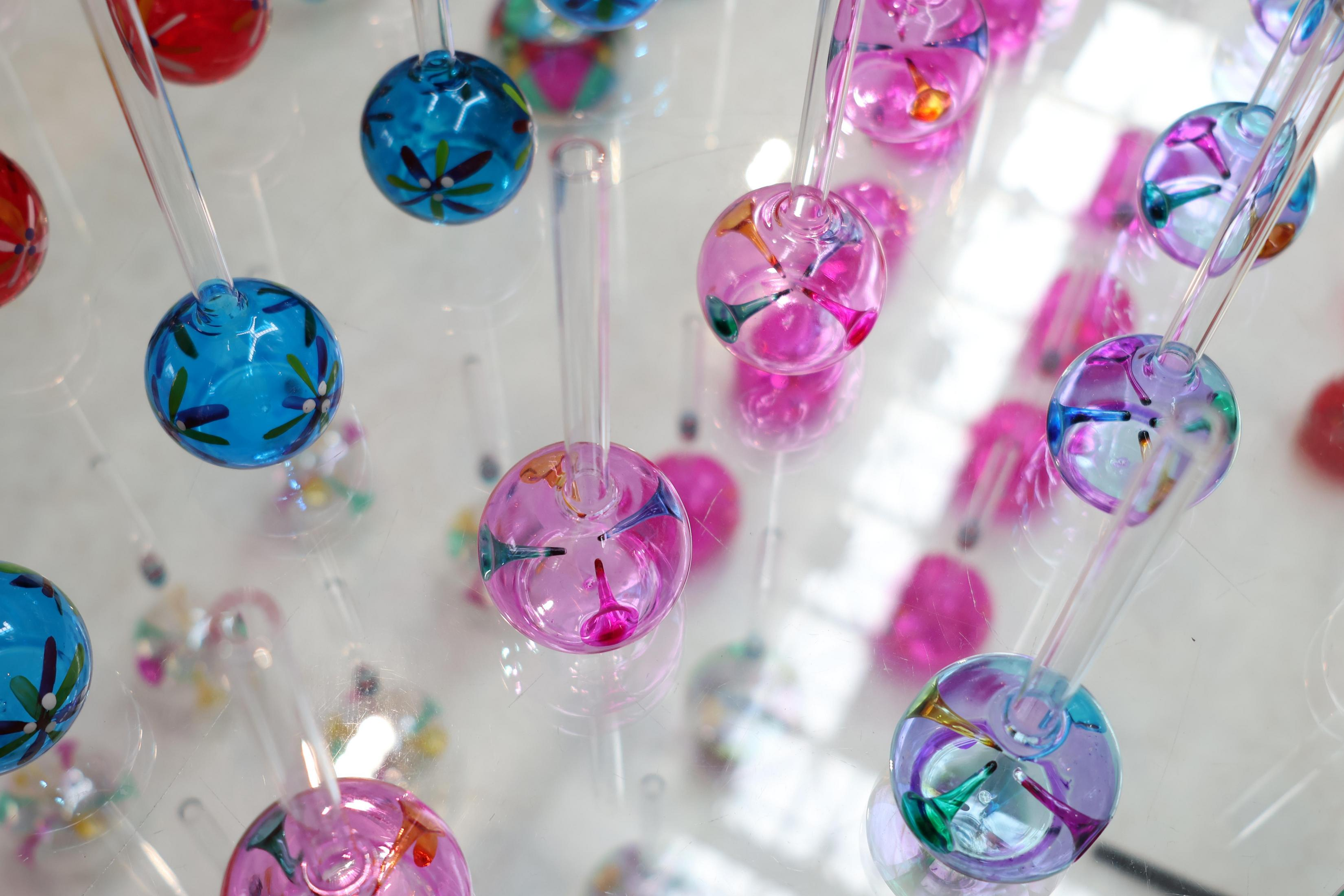 Renkli tasarımlara ve saplara sahip cam kürelerin yakın çekimi, çoğu odaklanmış ve bir araya getirilmiş.