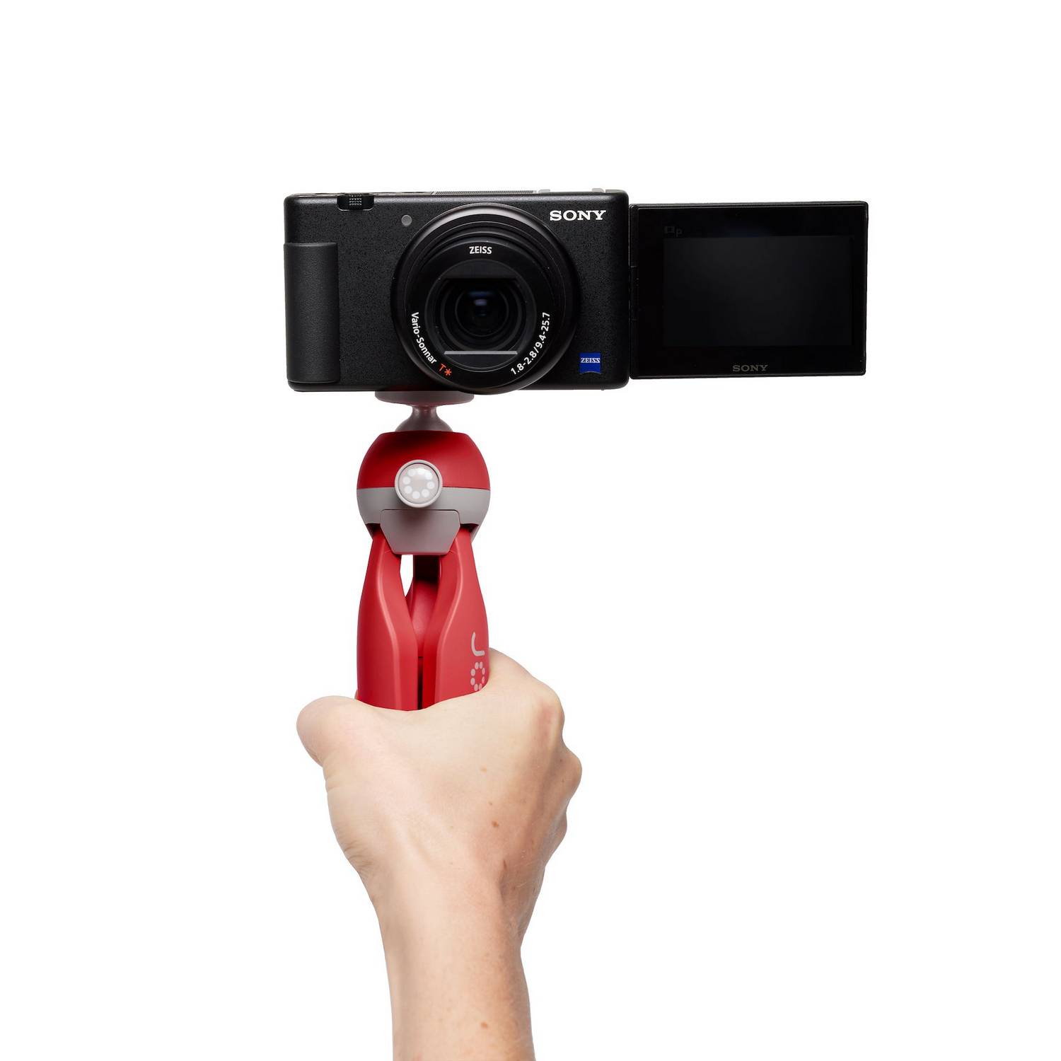 Hand holding a camera on a red tripod, white background.