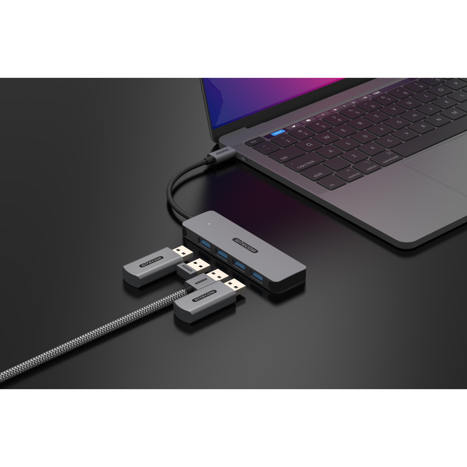 Een laptop aangesloten op een USB-hub en meerdere andere USB-apparaten. Op een zwart oppervlak.