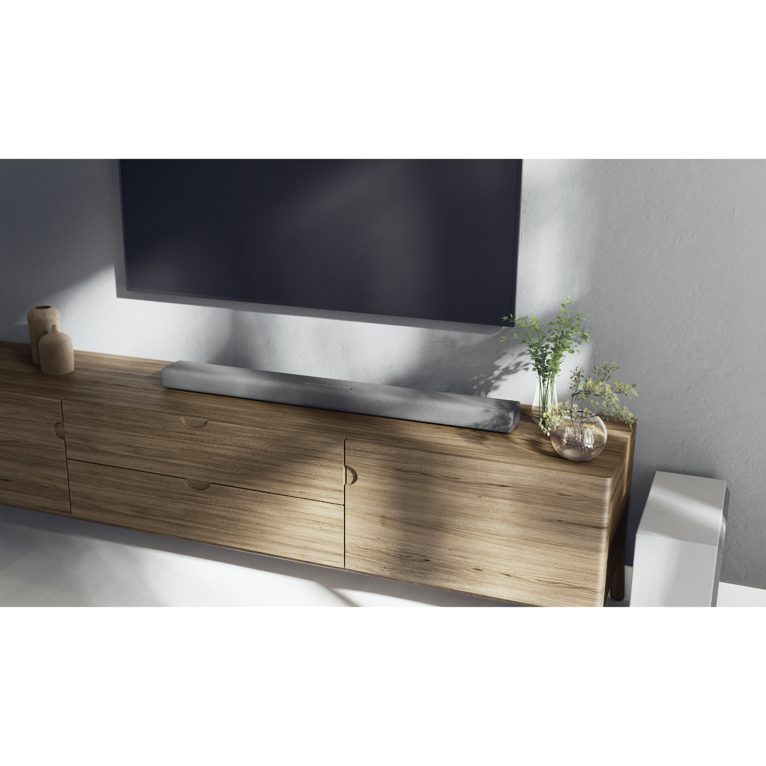 Una soundbar su un mobile in legno, con TV sopra e decorazioni con piante, in una stanza illuminata.