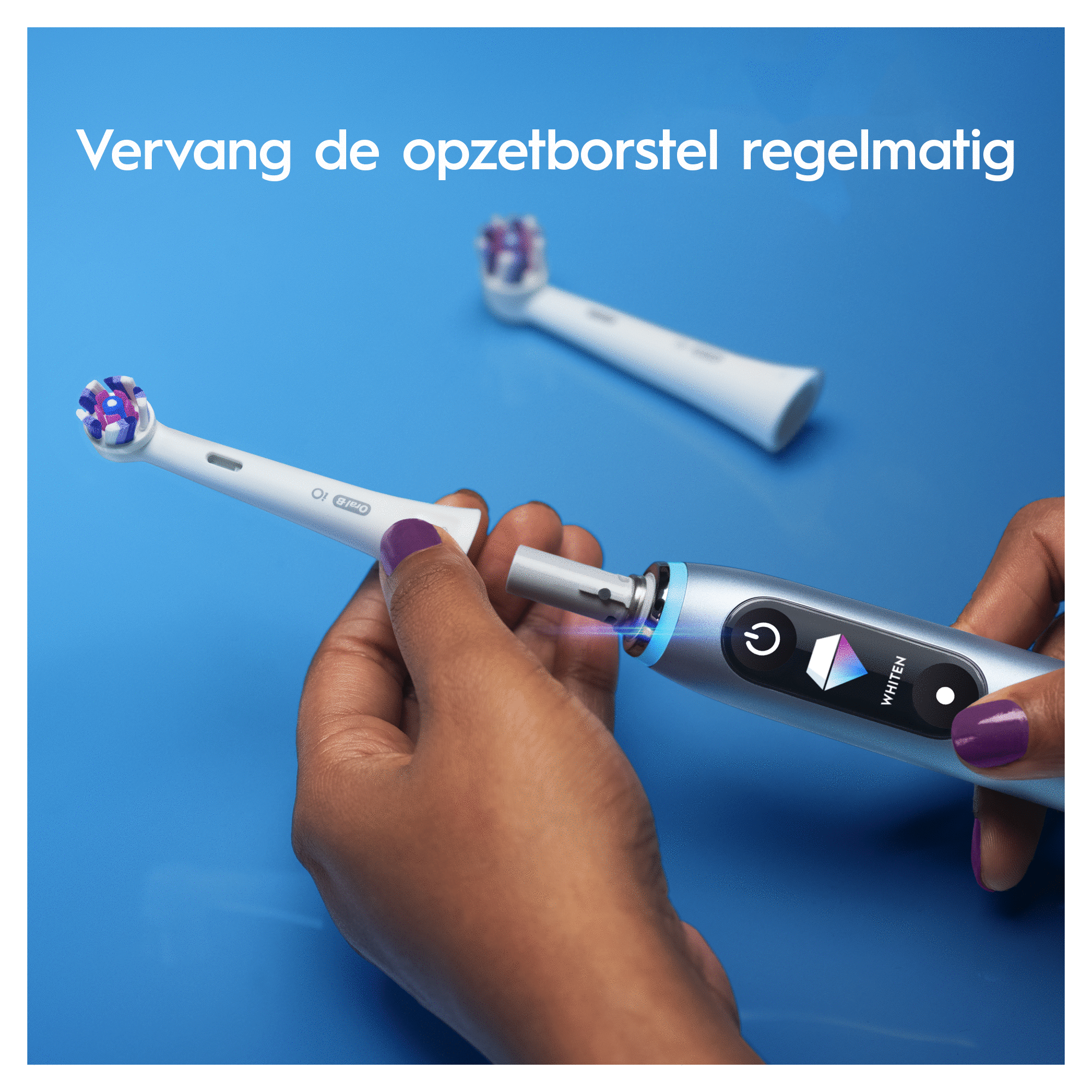 Ręce osoby wymieniającej główkę szczoteczki do zębów na tle niebieskim.