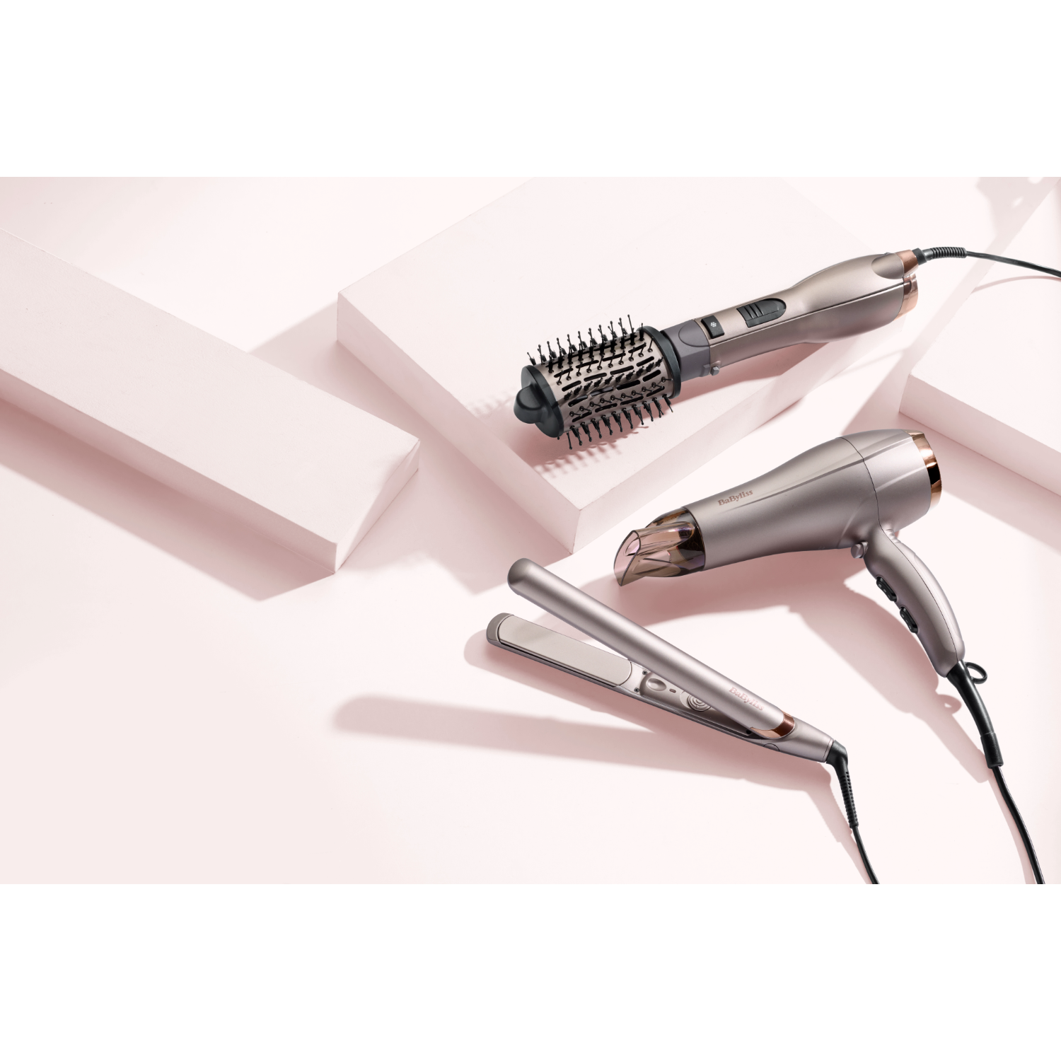 Strumenti per lo styling dei capelli: una spazzola arricciacapelli, un asciugacapelli e una piastra per capelli.