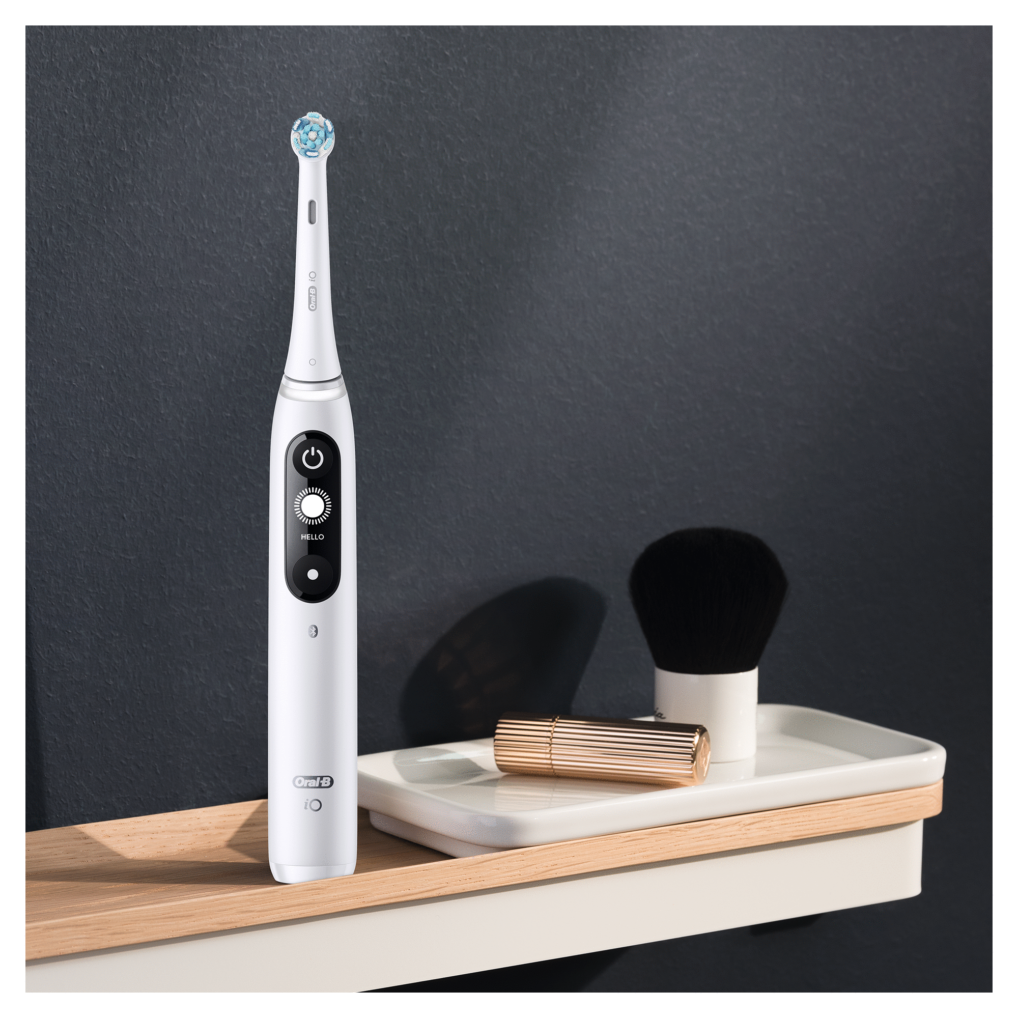 Cepillo de dientes eléctrico blanco con accesorios en un estante.