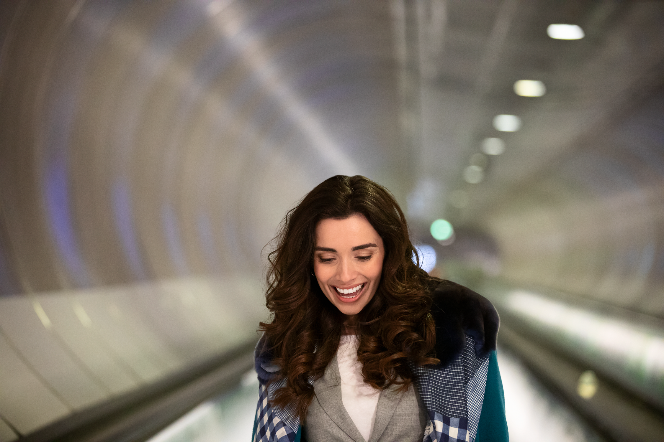 Mujer sonriendo en una escalera mecánica en un túnel.