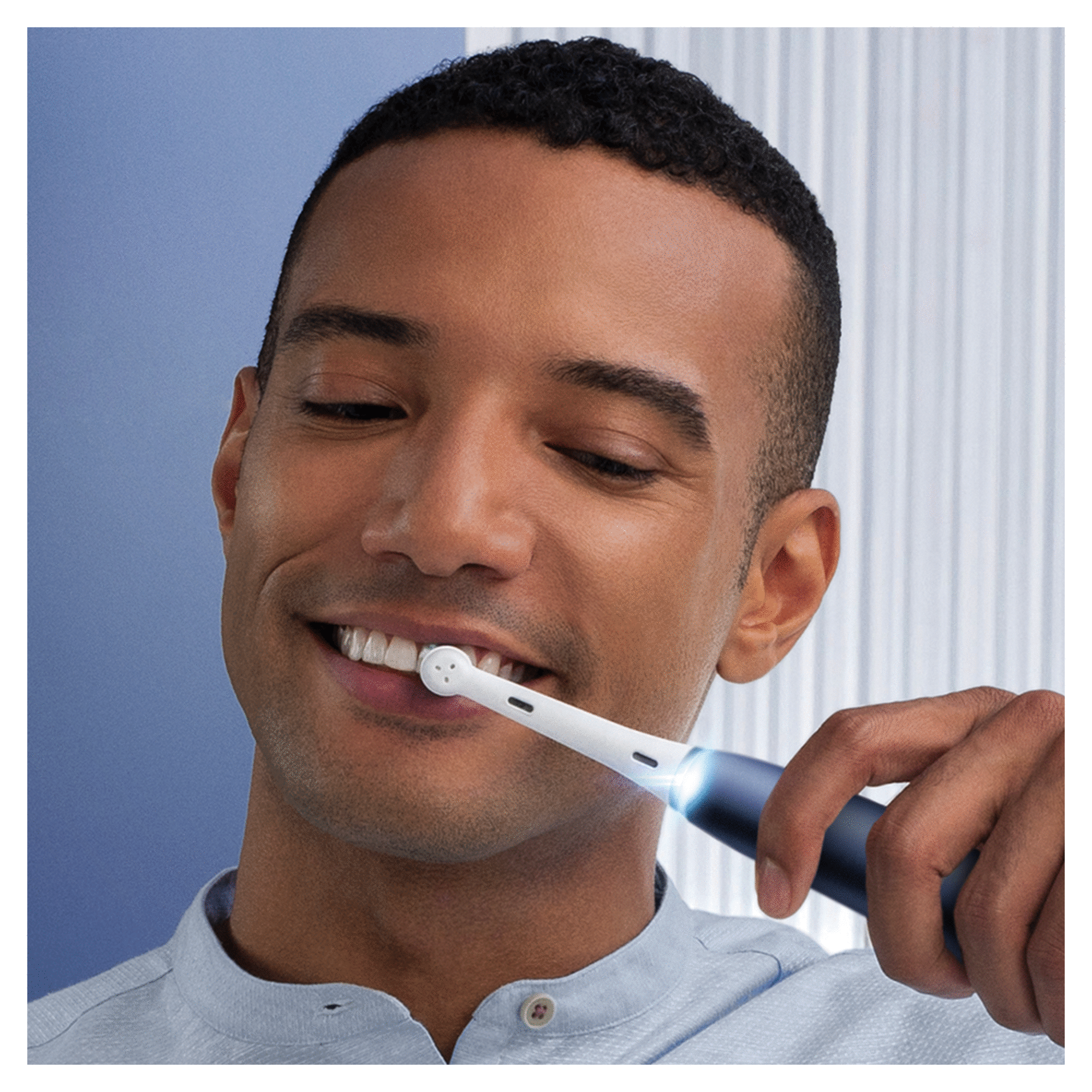 Uomo che si lava i denti con uno spazzolino elettrico. Lo spazzolino ha una luce sulla testina.