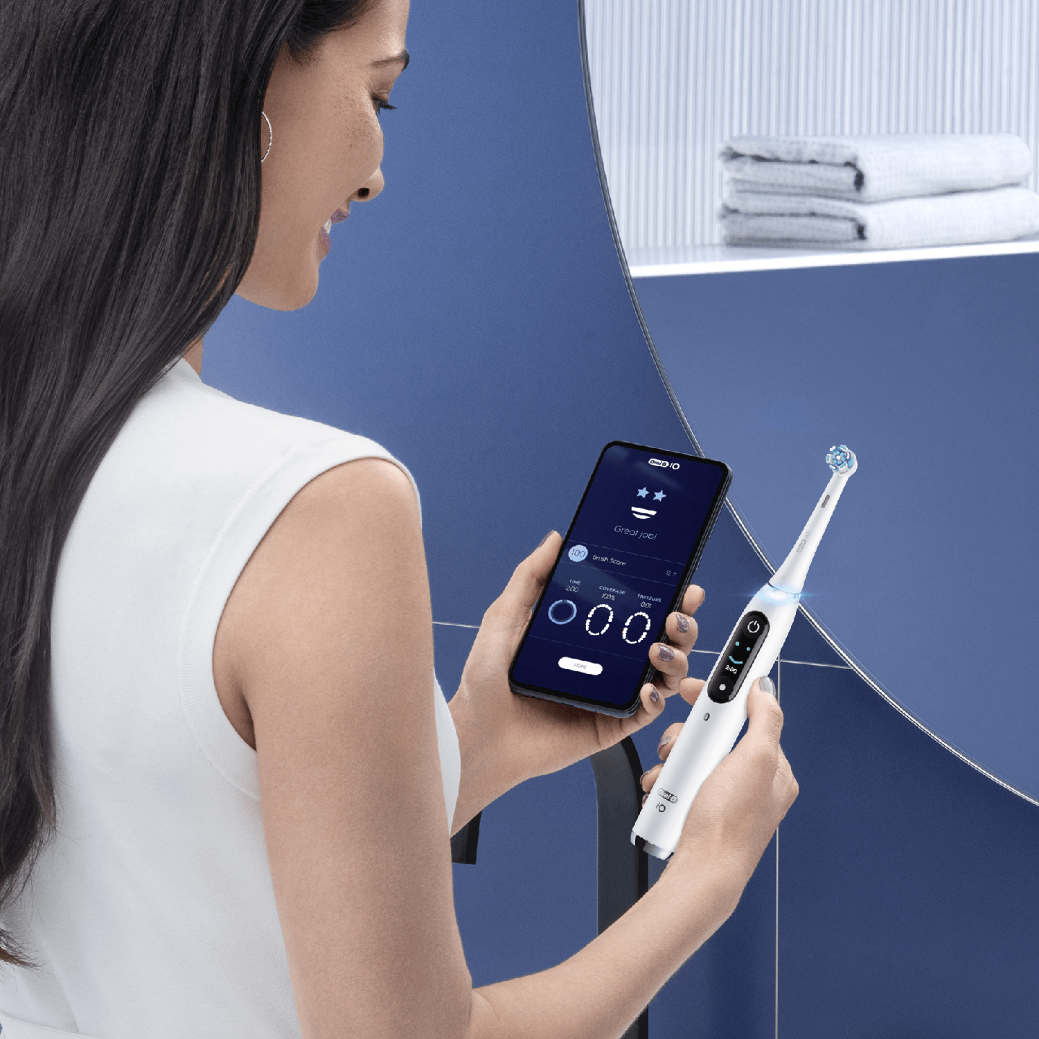 Donna usa spazzolino elettrico bianco, controllando i risultati sullo smartphone.