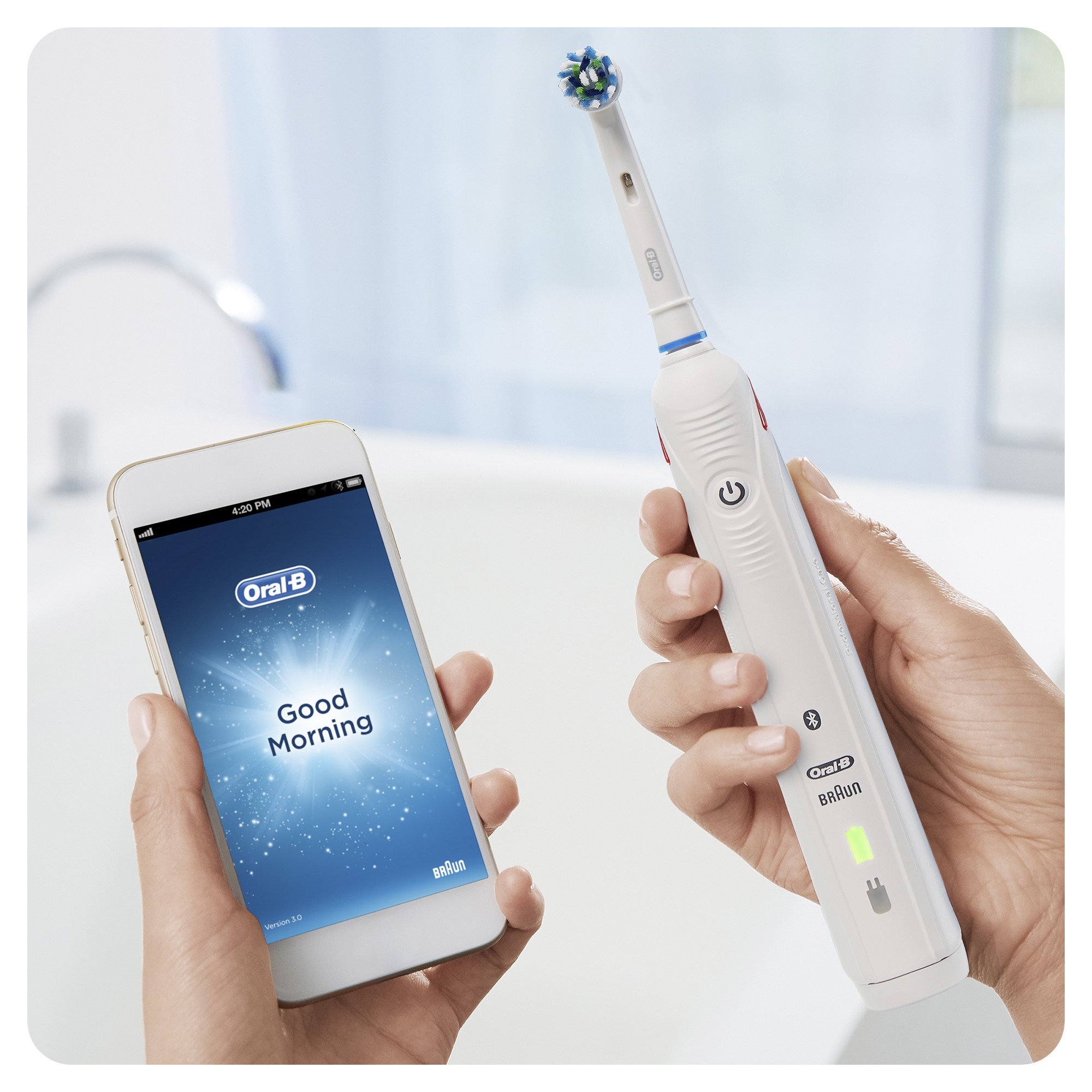 Persoon gebruikt elektrische tandenborstel naast een smartphone met 'Good Morning'.