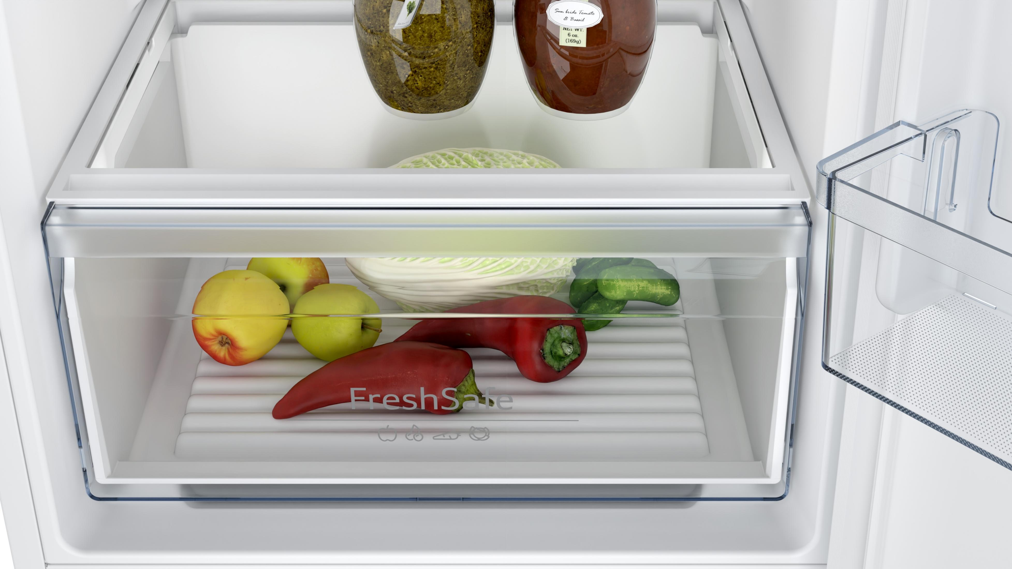 Koelkastlade gevuld met groenten: paprika's, appels en kool.