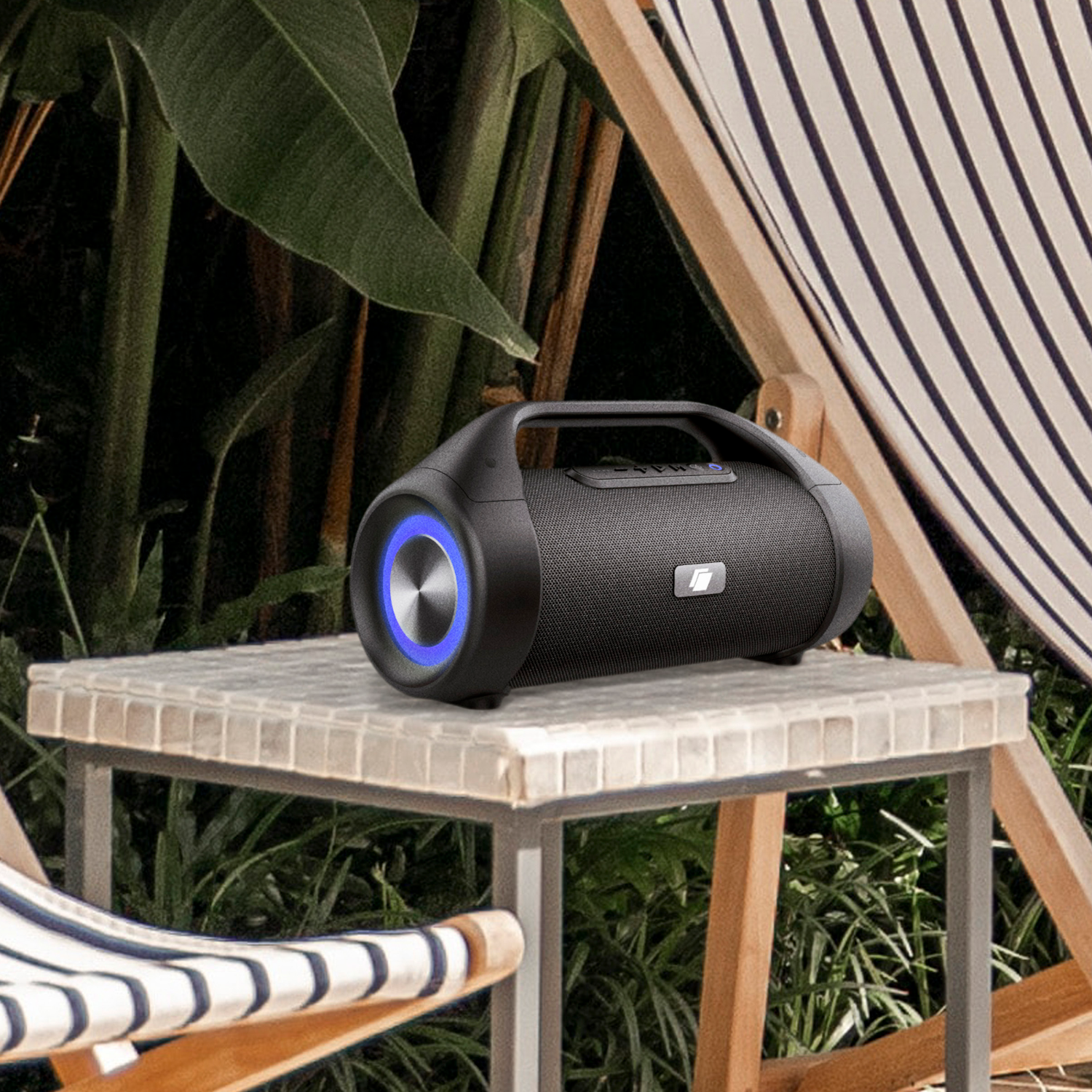 Zwarte speaker op tafel, blauw licht, in een tuin.