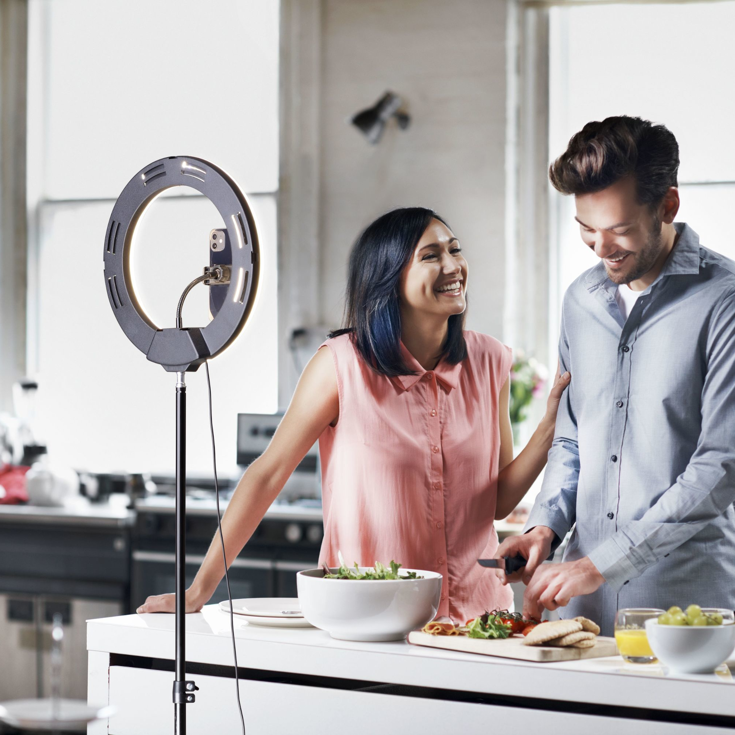 Dos personas cocinando en una cocina con aro de luz y encimera.