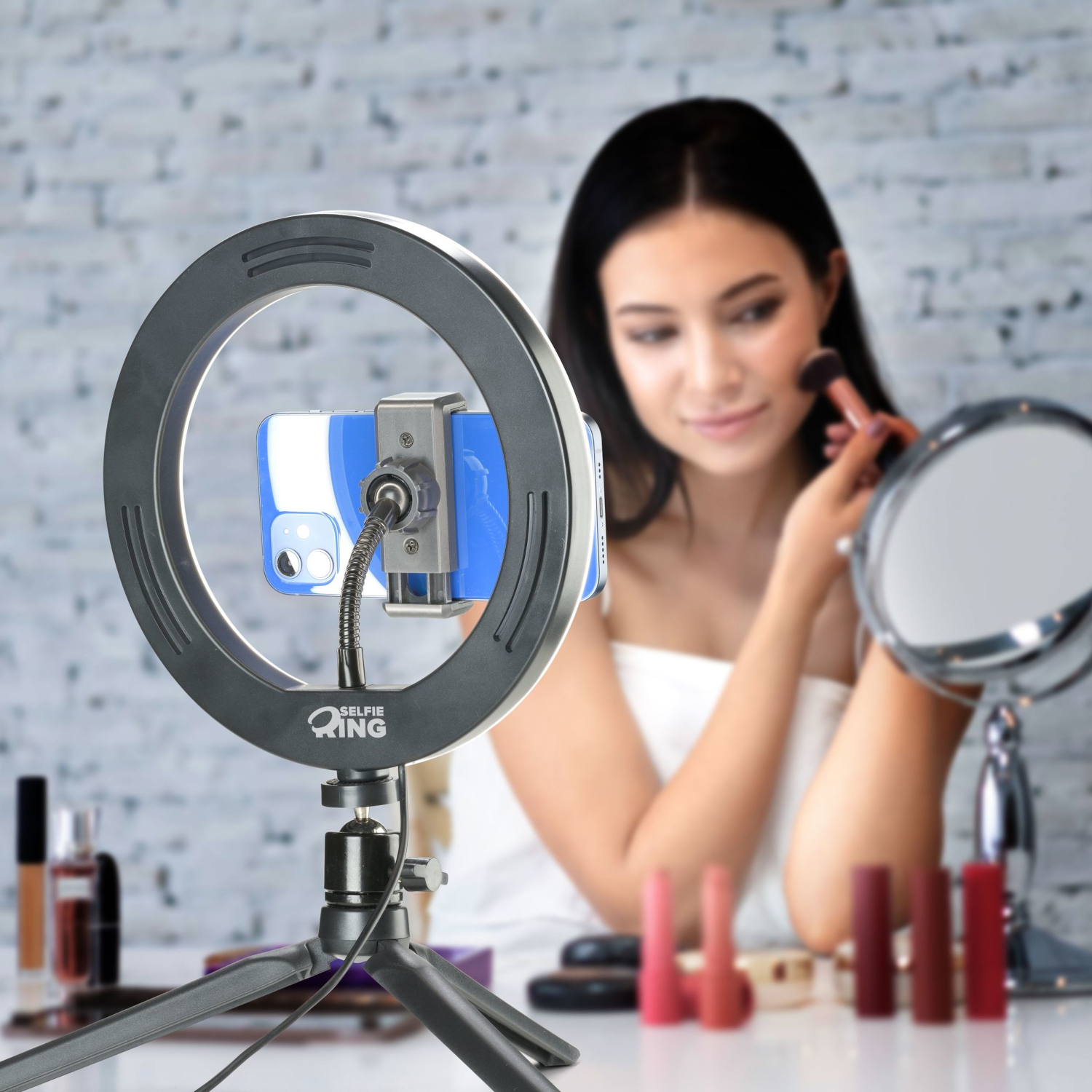 Una donna si trucca con un pennello usando una luce ad anello e un telefono come supporto.