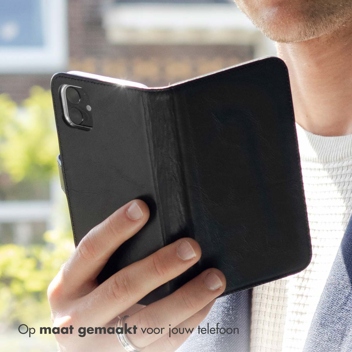 Eine Person hält eine schwarze Handyhülle mit einem schwarzen Telefon. Die Hülle ist geöffnet.