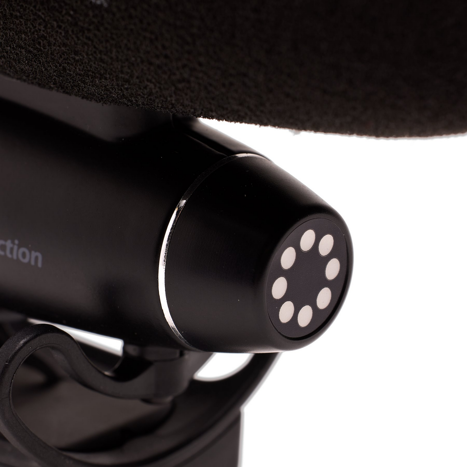 Gros plan sur un microphone noir avec un pare-brise noir flou. Le microphone a une tête circulaire.