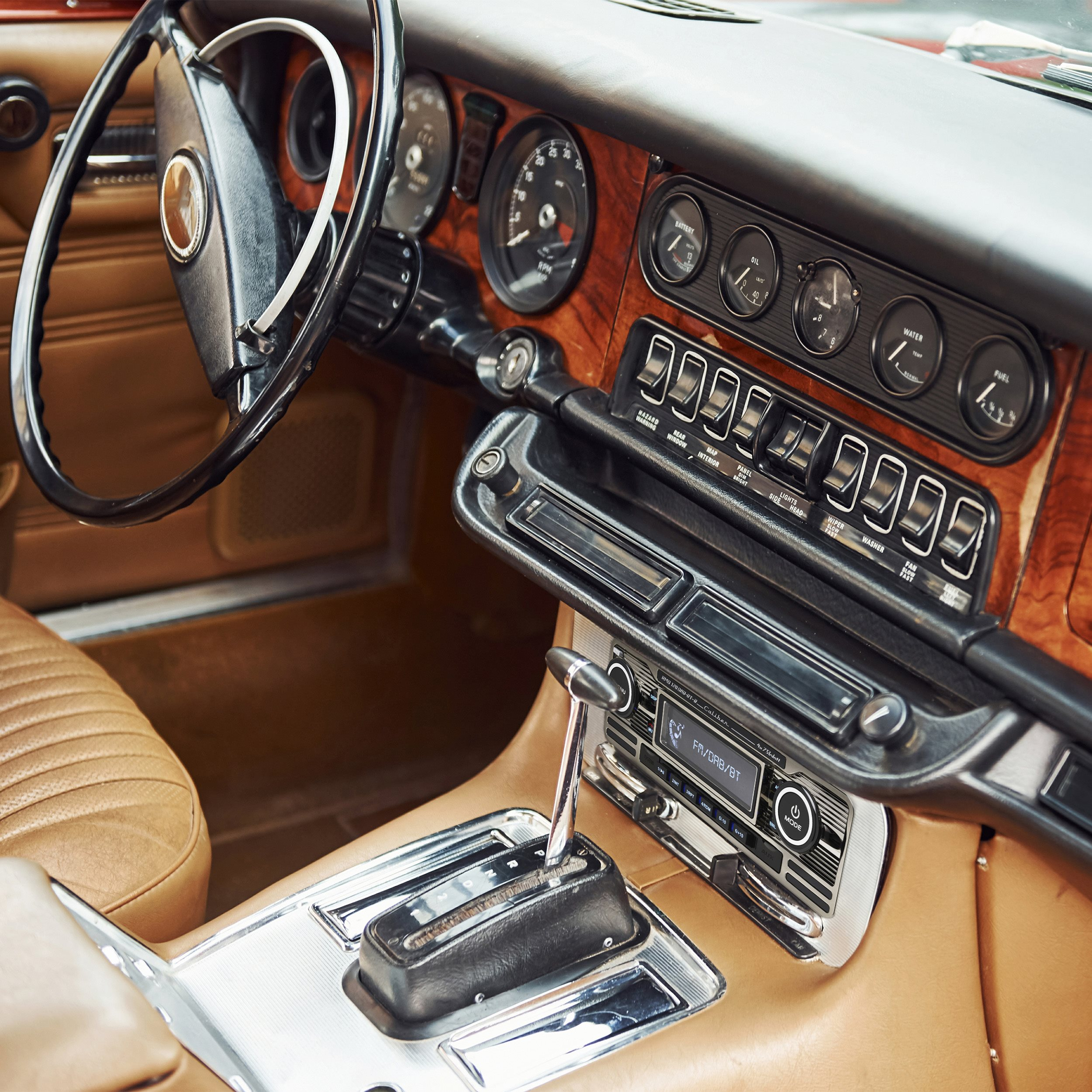 Interior of a classic brown car with wood trim, steering wheel, and dashboard.