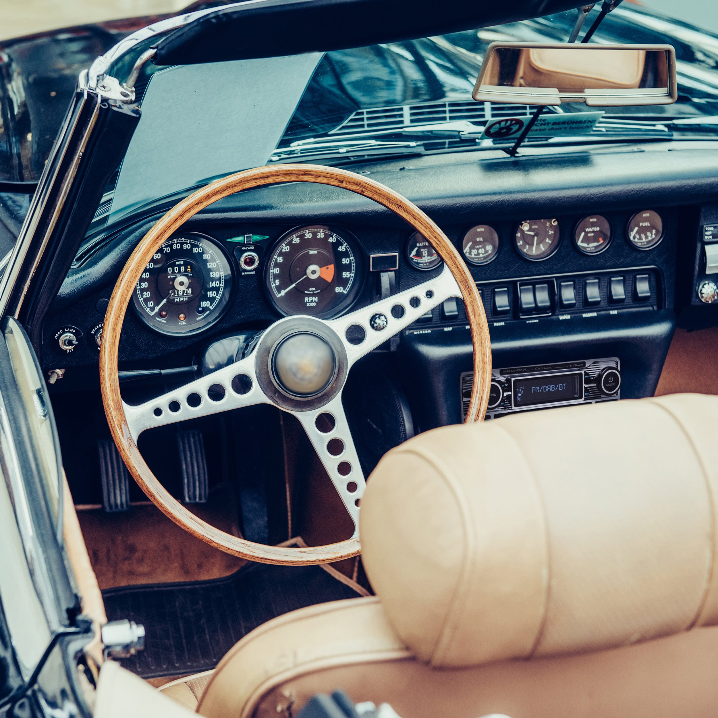 Interior of a classic car with a wooden steering wheel.
