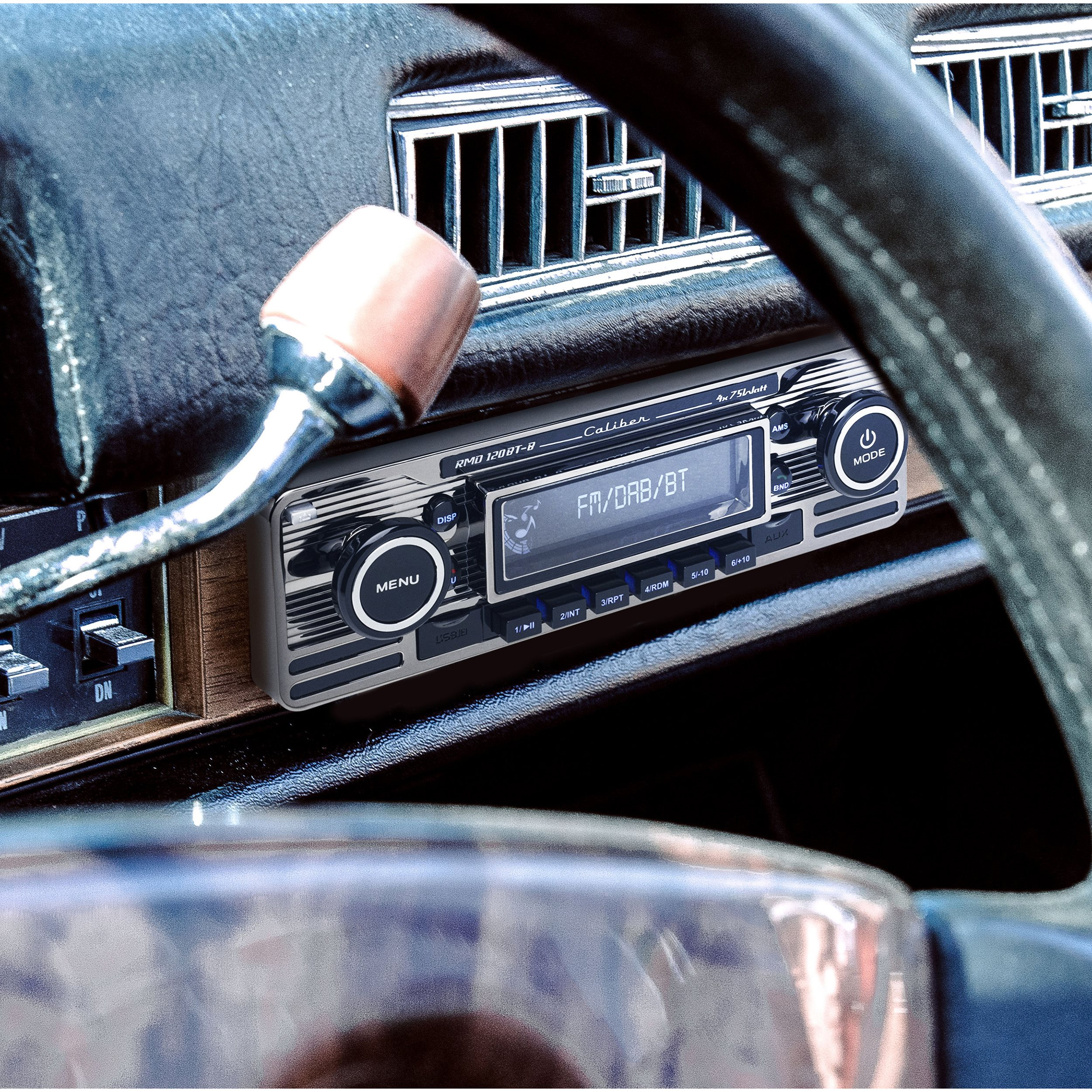 Car radio. It is metallic silver. It has a screen, buttons and a dial. The car's interior is visible.