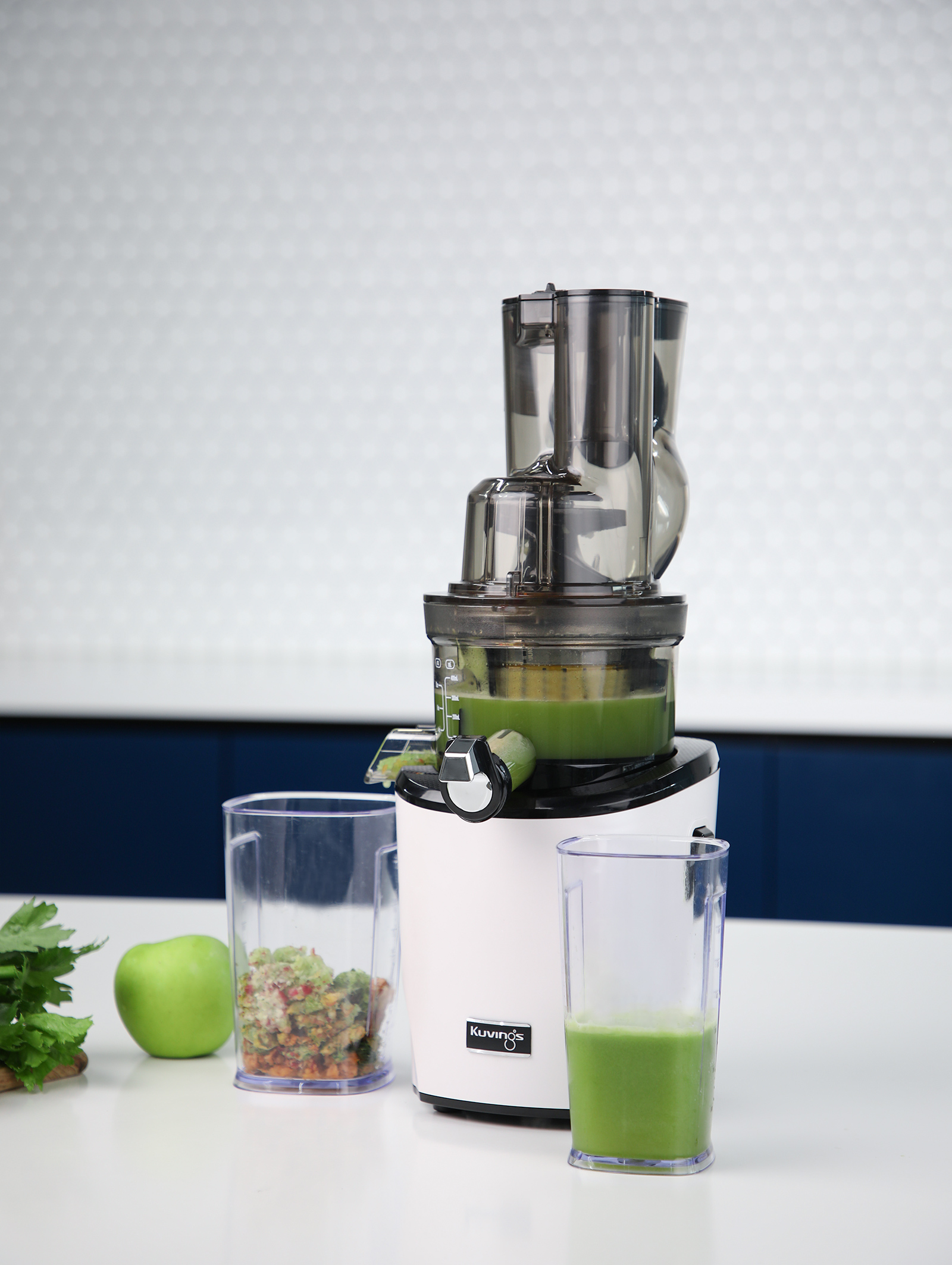 Exprimidor blanco y negro con jugo verde. Manzana y pulpa delante.