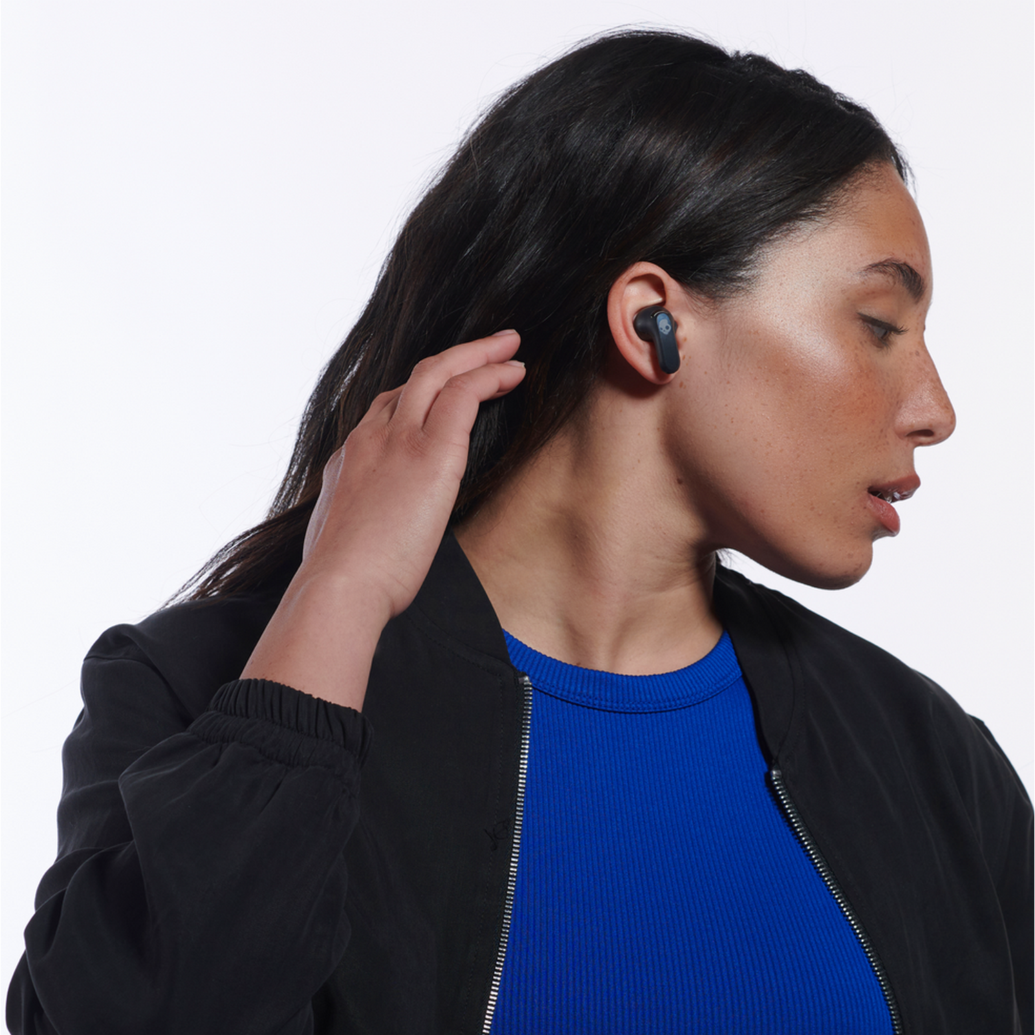 Kobieta w niebieskiej koszuli i czarnej kurtce, z jednym pączkiem w uchu.