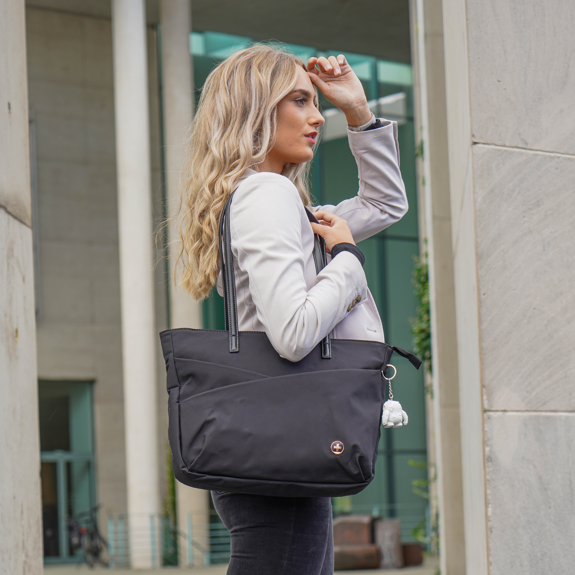 Donna bionda con borsa nera fuori, che guarda altrove. Edificio sullo sfondo.