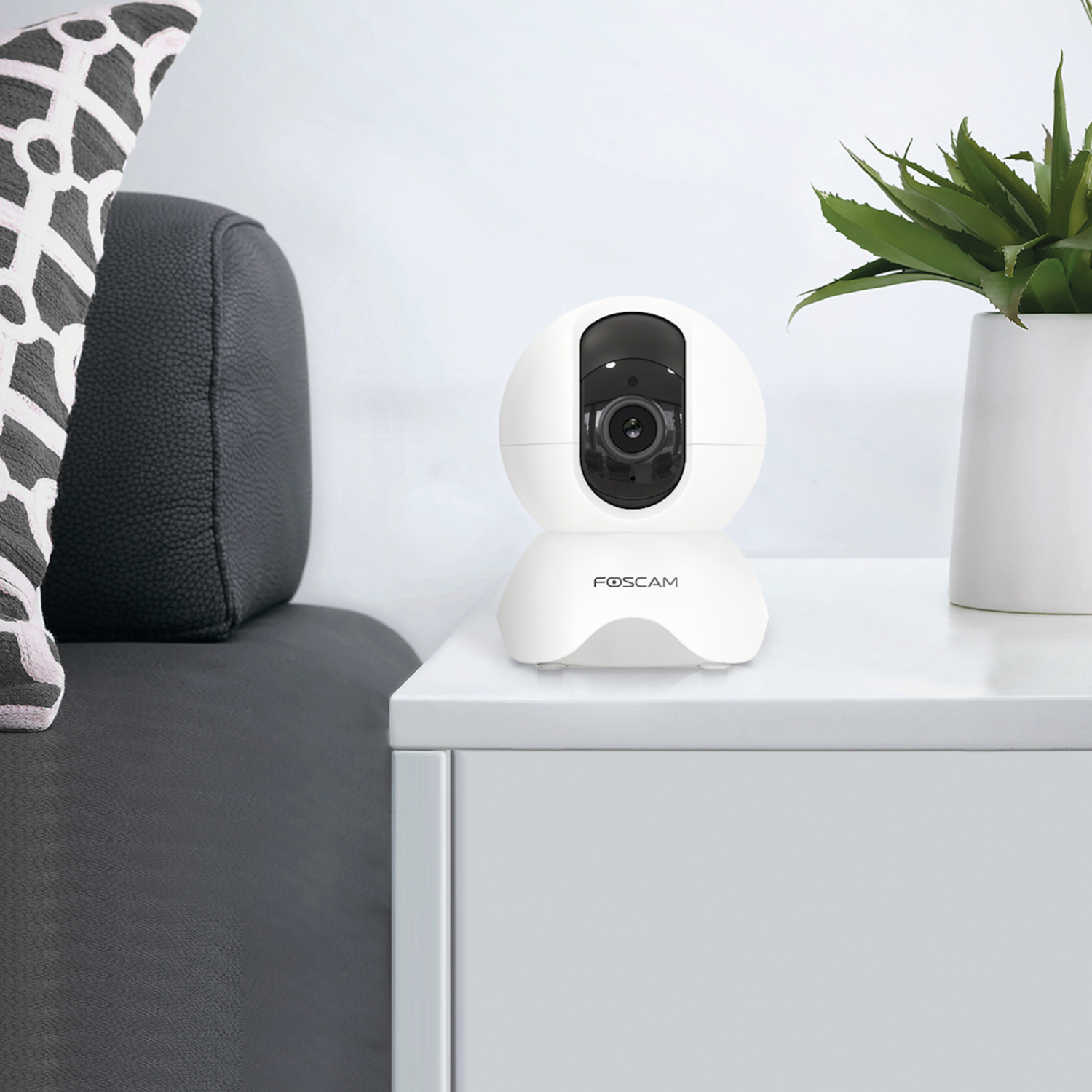 White security camera on a white table. Black camera lens. FOSCAM logo below.