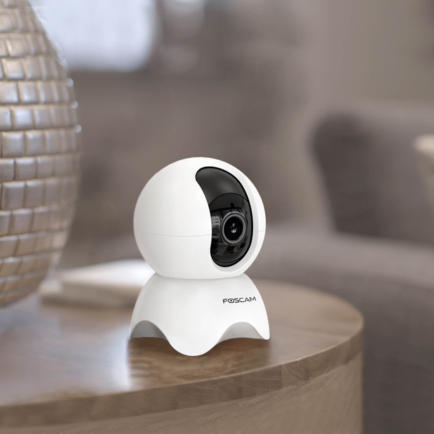 White security camera on a table. Modern design, round shape, with a black lens.
