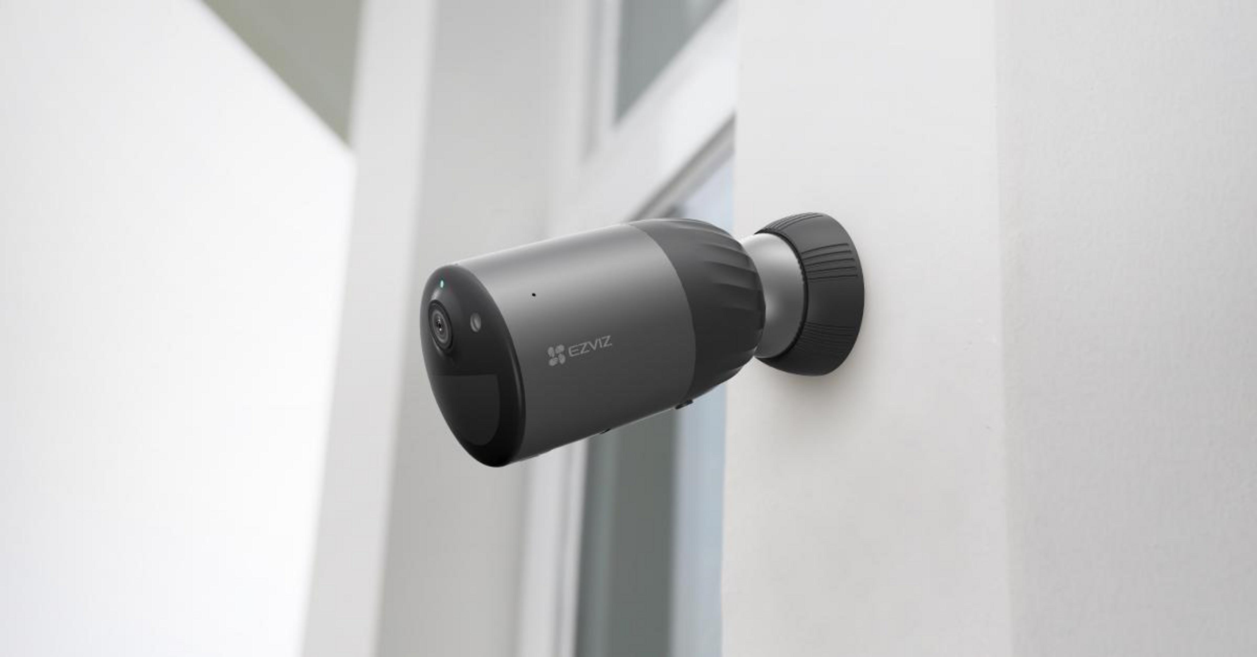 Szara cylindryczna kamera bezpieczeństwa na białej ścianie, pod kątem.