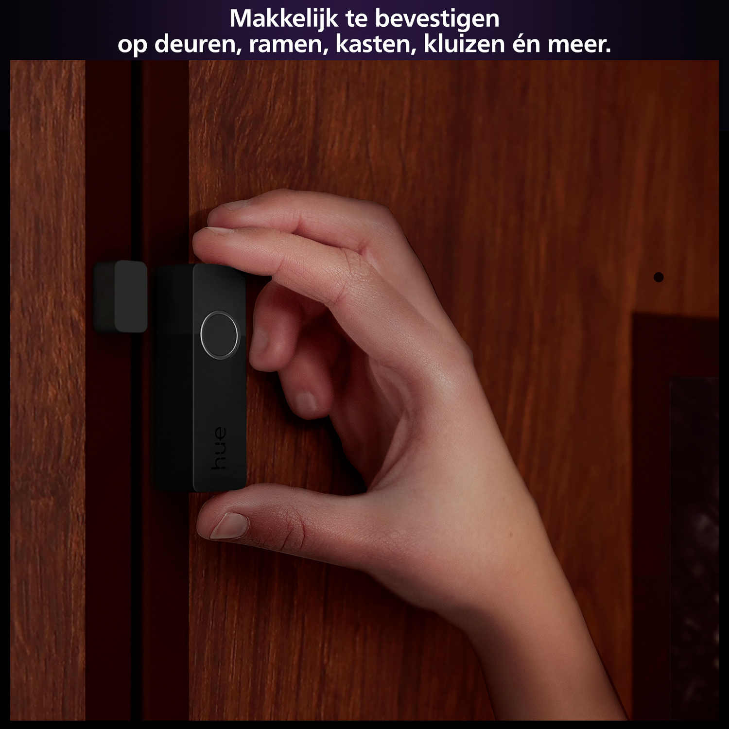 Czarny czujnik hue jest przymocowywany do brązowych drzwi. Tekst w języku niderlandzkim.