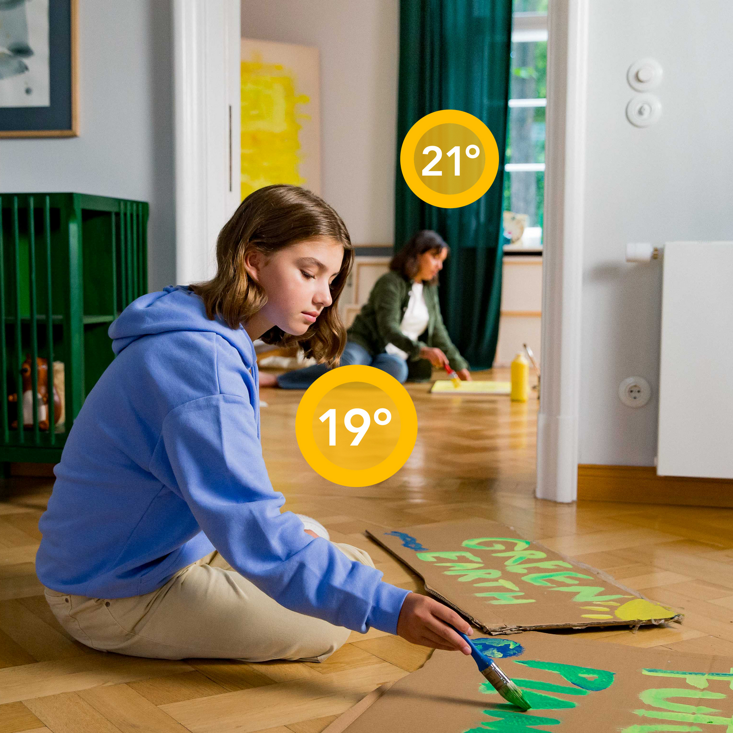 Twee mensen schilderen kartonnen borden in een kamer. Temperaturen van 19 en 21 worden weergegeven.